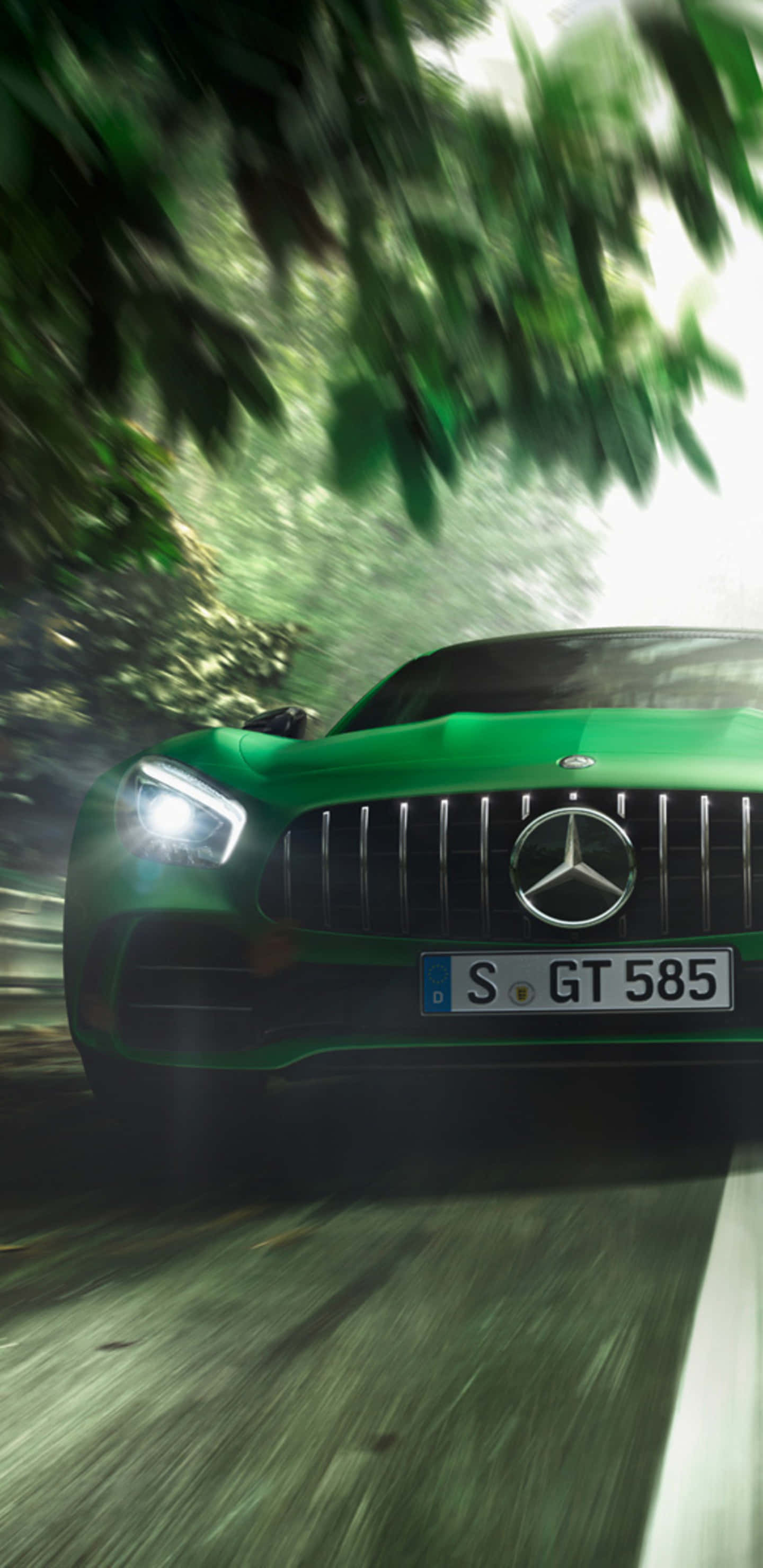 綠色梅賽德斯穿行樹林 Pixel 3XL AMG GT-R 背景 壁紙 — 一輛充滿活力的綠色 Mercedes-AMG GT 在茂密的森林中疾馳，樹葉和道路呈現動態模糊效果。