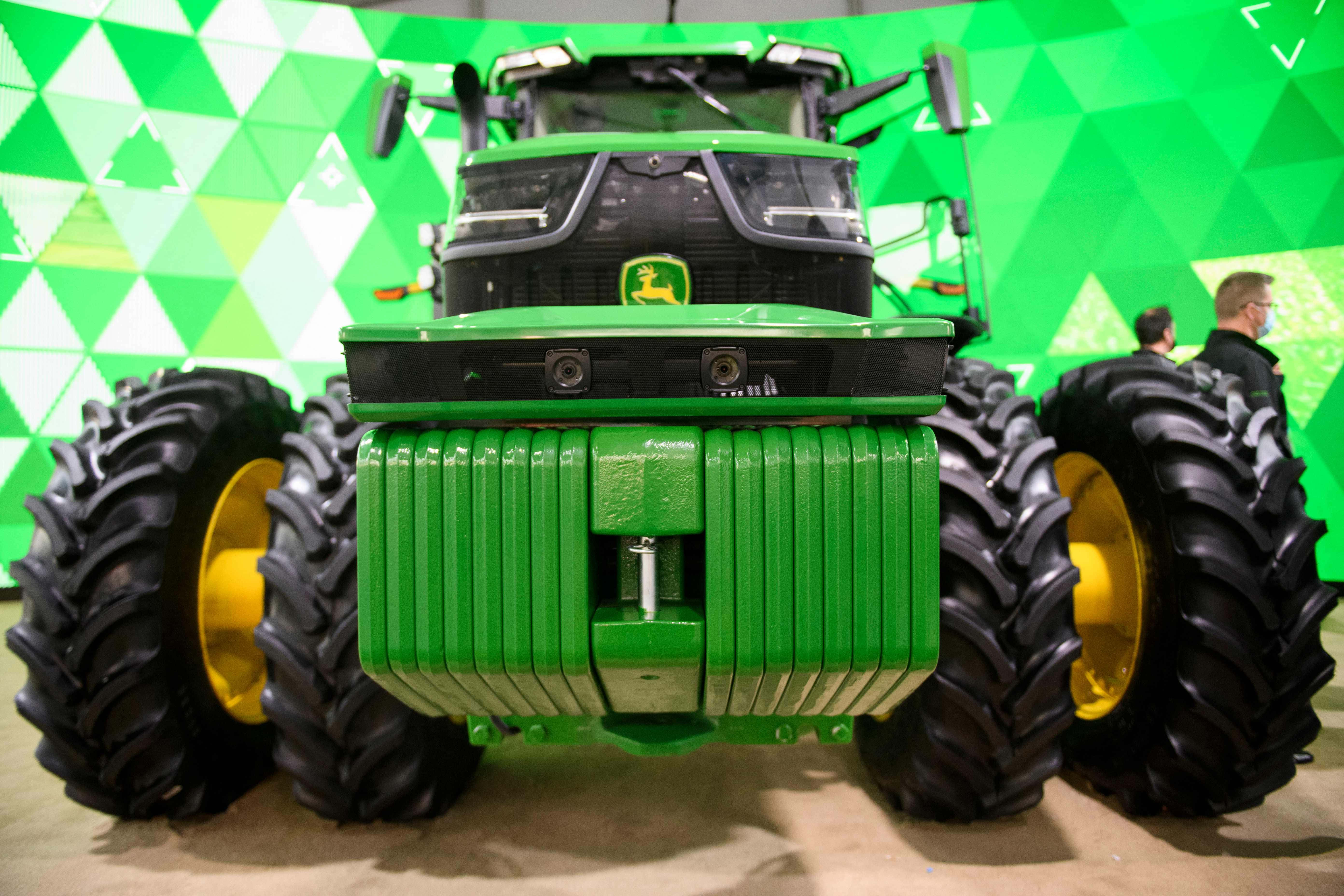 John Deere 桌布 壁紙 — 綠色約翰迪爾拖拉機配黃色輪子的特寫，背景為幾何綠色和白色。