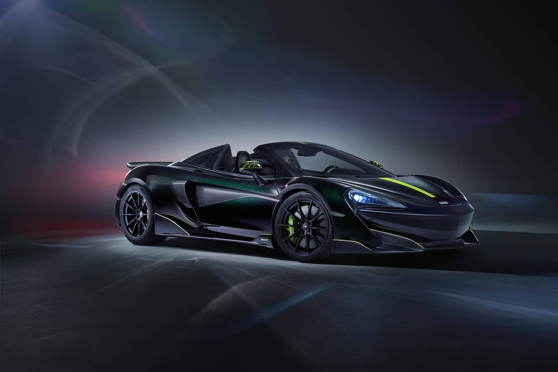 在黑暗的工作室環境中，黑色McLaren跑車帶有綠色亮點。