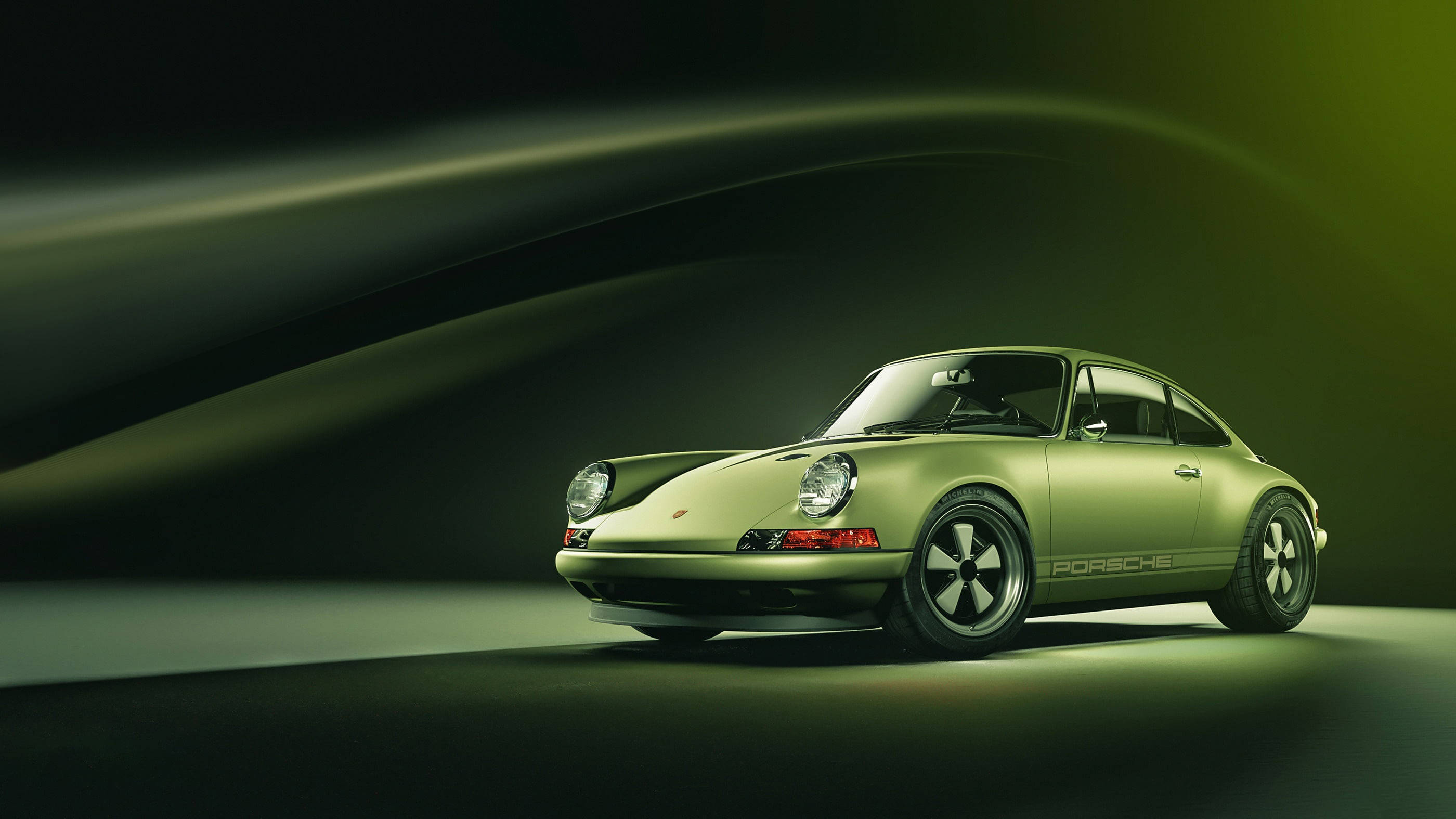 綠色美學Singer Porsche 壁紙 — 一輛時尚的復古綠色保時捷911在戲劇性的工作室燈光下，在深色漸變背景中閃耀。