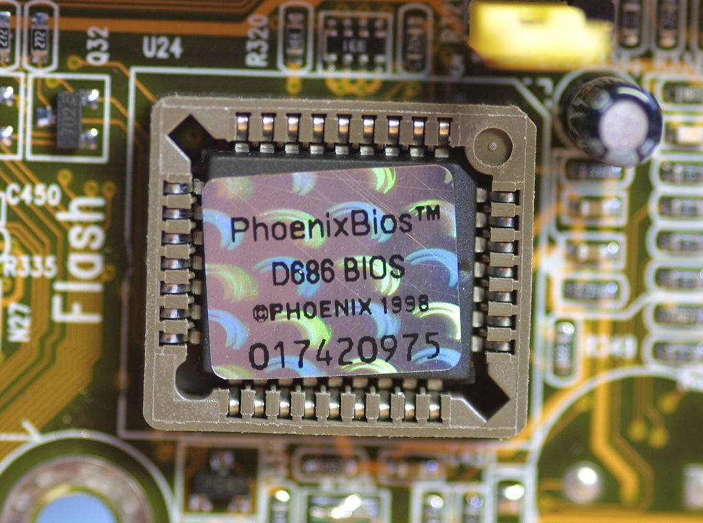 Phoenix 1998 BIOS 壁紙 — 綠色電路板上Phoenix BIOS晶片的特寫，可見焊點和組件標籤。