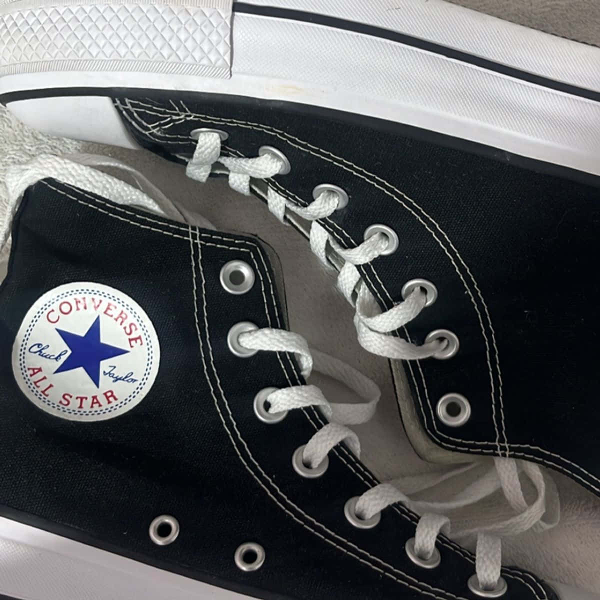 綠色高筒匡威鞋，展現時尚宣言 壁紙 — 黑色 Converse Chuck Taylor All Star 運動鞋特寫，配有白色鞋帶和縫線，背景為中性色調。
