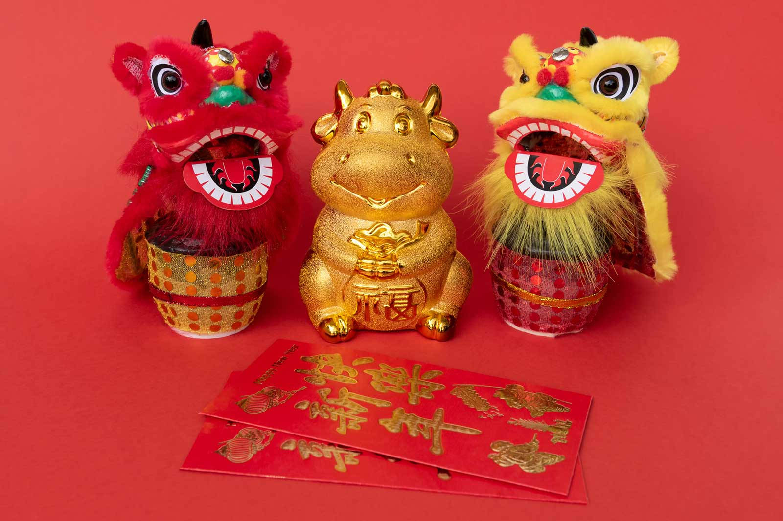 三件舞獅服裝和一個金色牛公仔，附有紅包，用於中國新年。