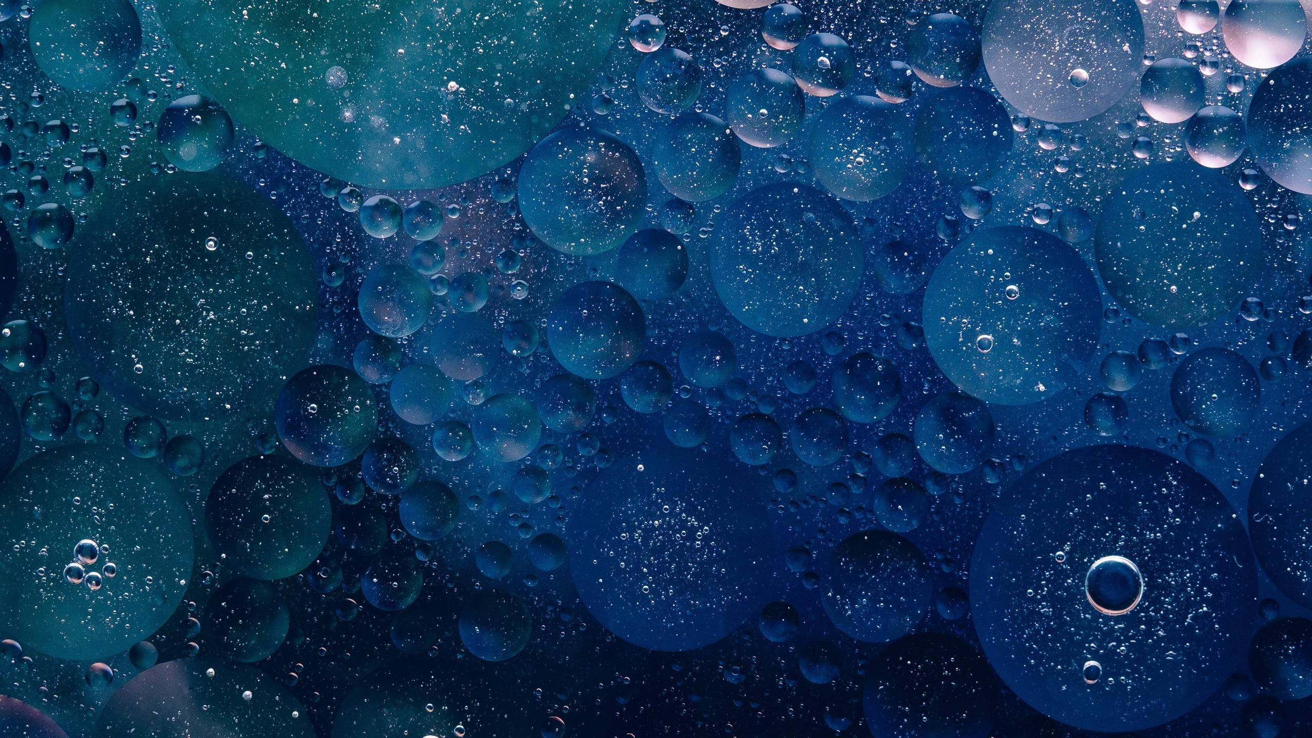 綠藍色氣泡紋理壁紙 壁紙 — 令人著迷的微距特寫，呈現帶有閃爍粒子的虹彩藍色油泡在水中漂浮。