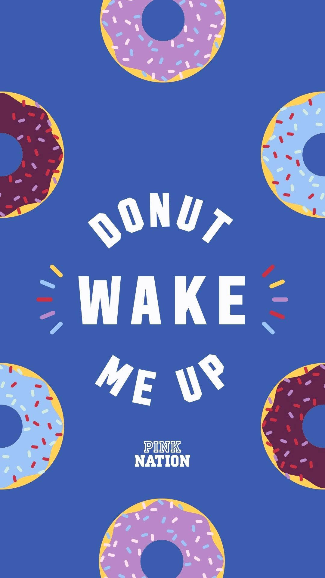 維多利亞的秘密甜甜圈別吵醒我 壁紙 — 粗體白色文字 'DONUT WAKE ME UP' 居中於藍色背景，周圍漂浮著色彩繽紛的糖霜甜甜圈。