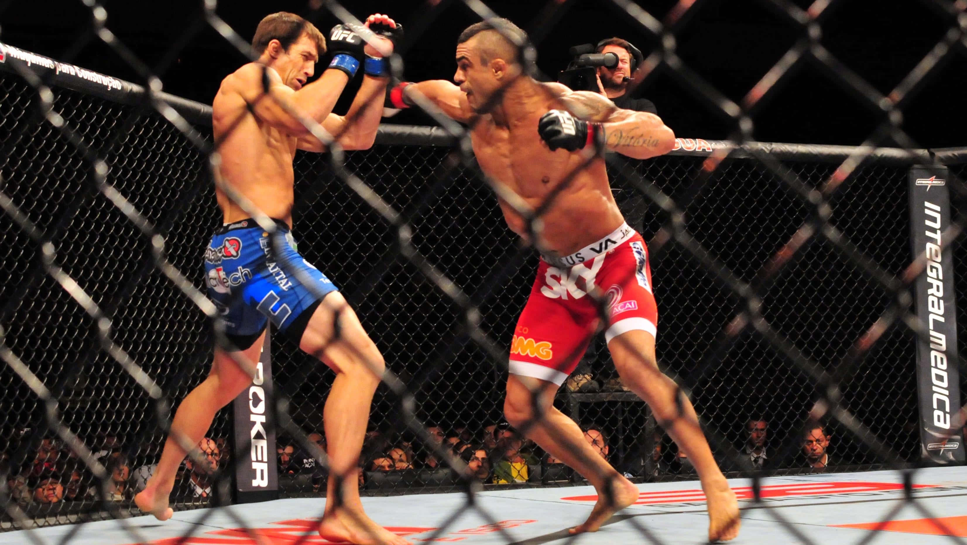 維托·貝爾福特對戰盧克·羅克霍德 UFC On FX 壁紙 — 兩名拳手在籠中交鋒，其中一人在混合武術比賽中擊中對手一拳。