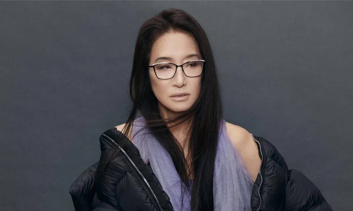 戴眼鏡穿黑色外套的女性，身穿紫色上衣的攝影棚肖像。