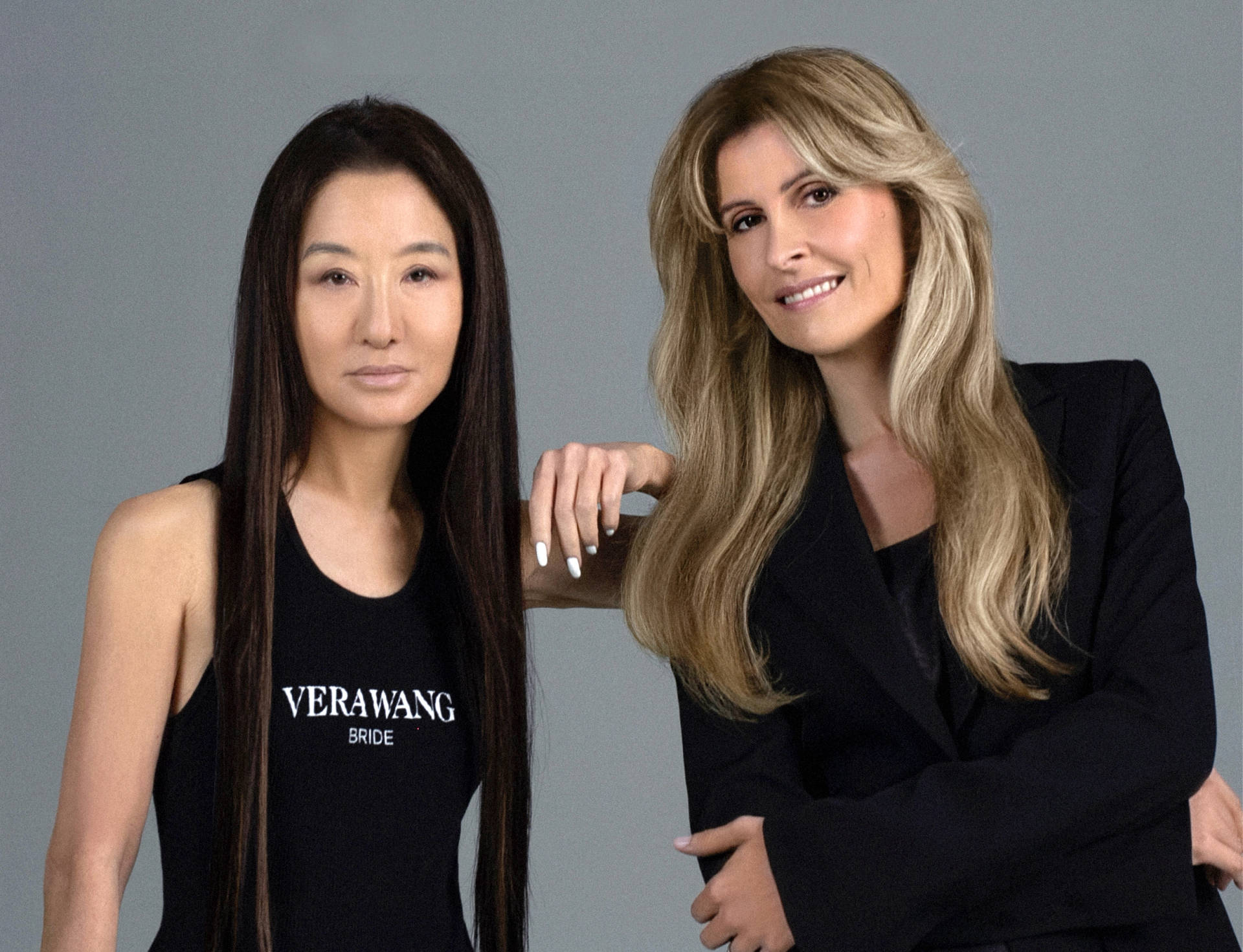 兩位身穿黑色服裝的女性為工作室肖像擺姿勢，其中一位穿著 Vera Wang Bride 背心。