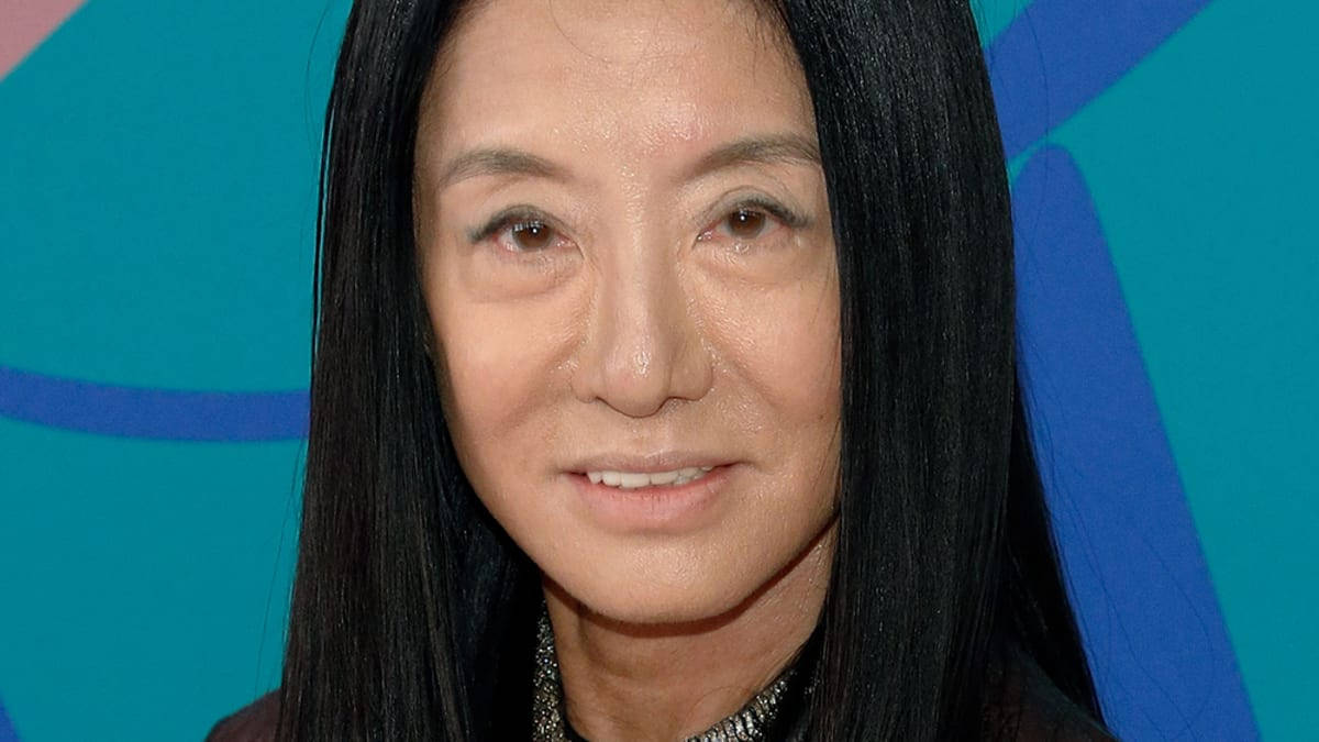 長黑髮女性喺色彩繽紛嘅抽象背景前微笑。