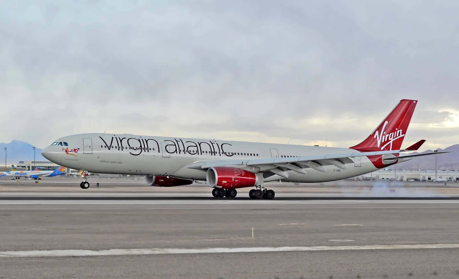 維珍航空A330客機起飛 壁紙 — 維珍航空空中巴士A330-300在陰天的機場停機坪滑行，背景有遠山。