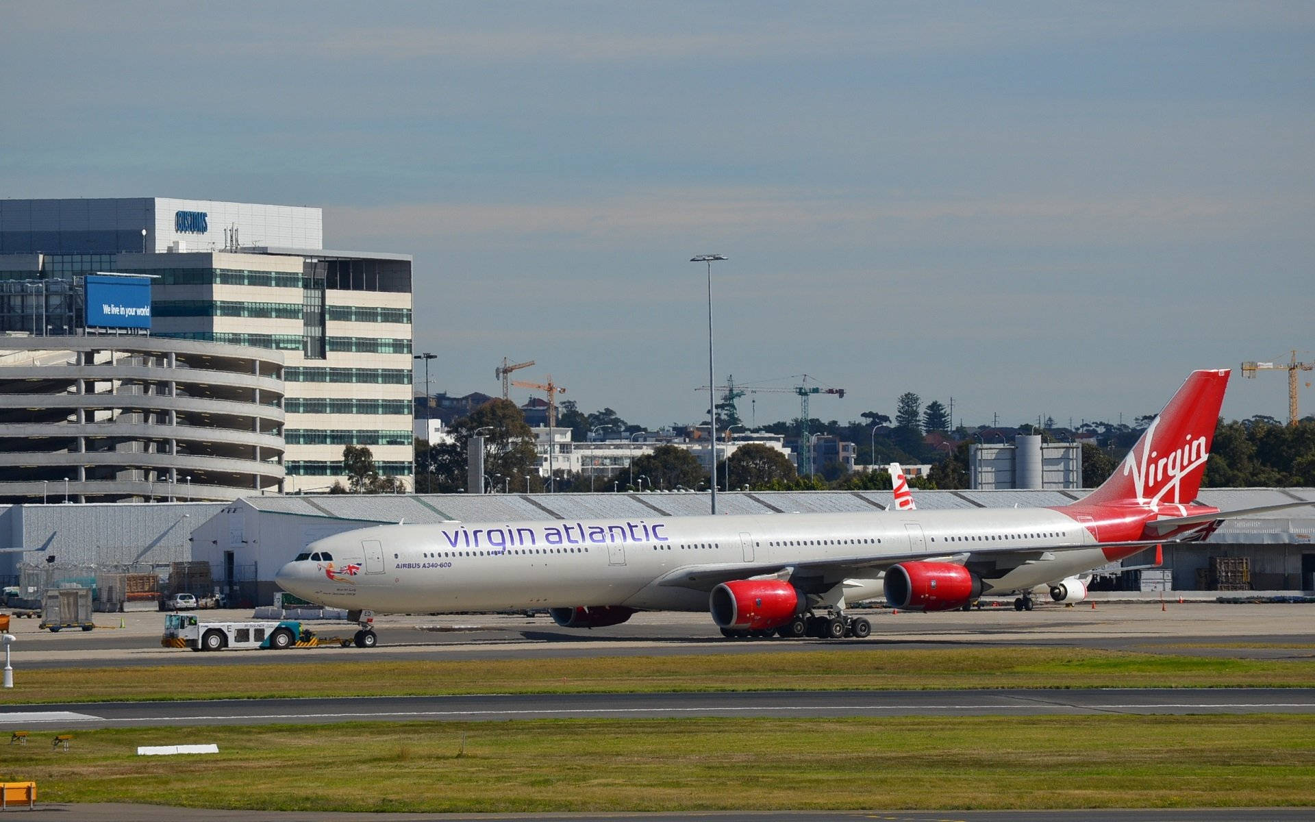 維珍航空飛機在機場停機坪上，背景有客運大樓。