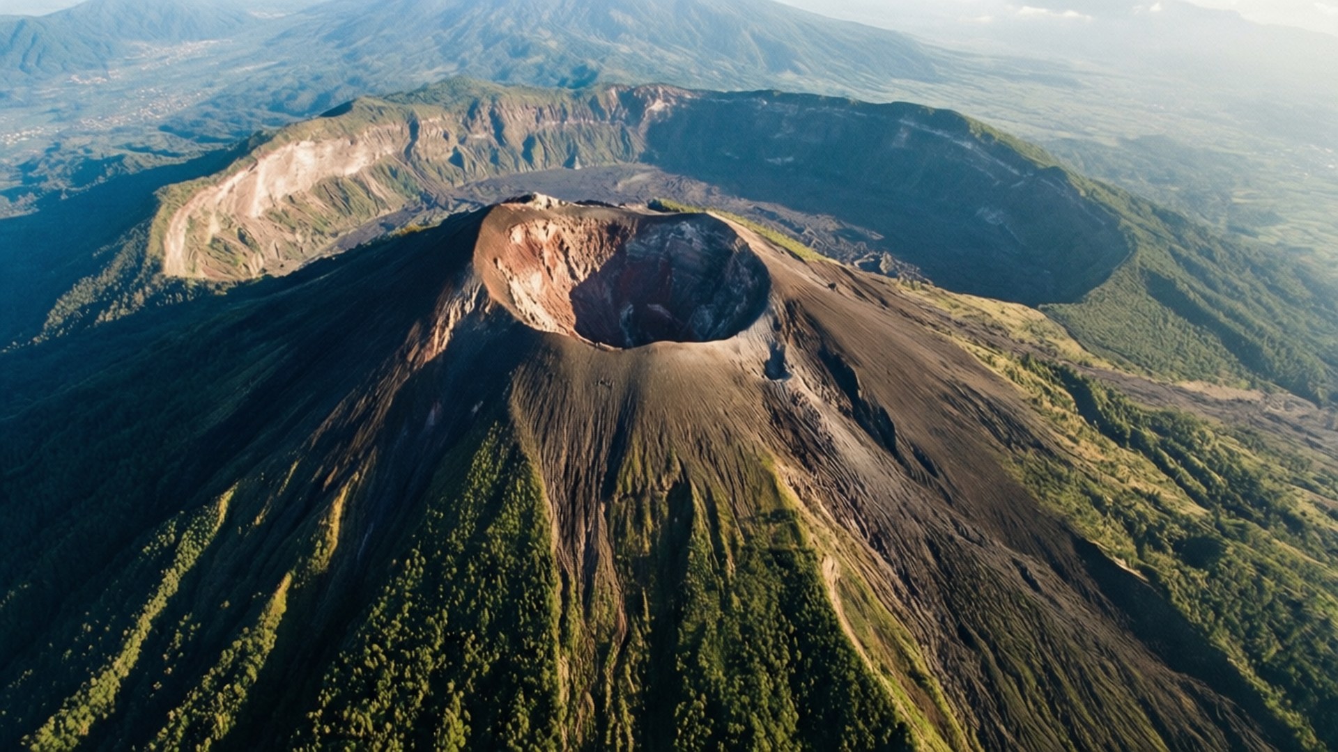 一個火山口嘅航拍圖，斜坡被灰燼覆蓋，周圍係綠色森林。