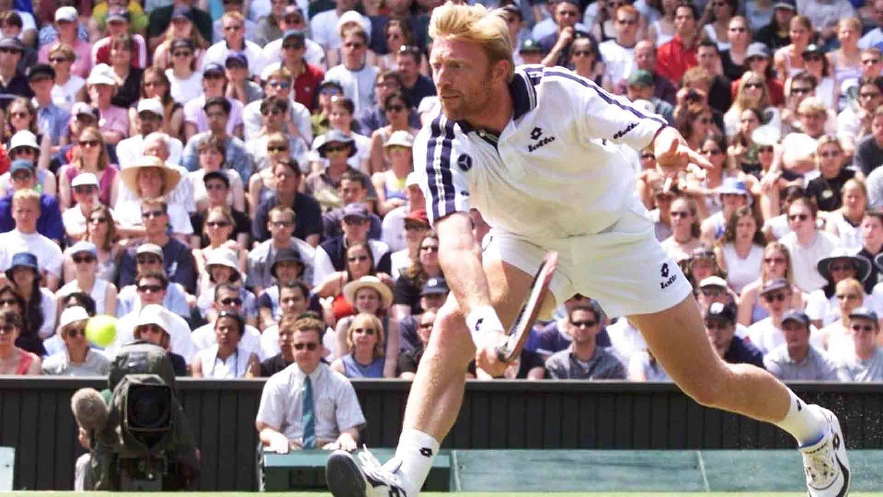 網球巨星鮑里斯·貝克爾 壁紙 — 一名男性網球選手在草地上揮拍中途向前撲出，滿座觀眾在明亮的日光下觀看。