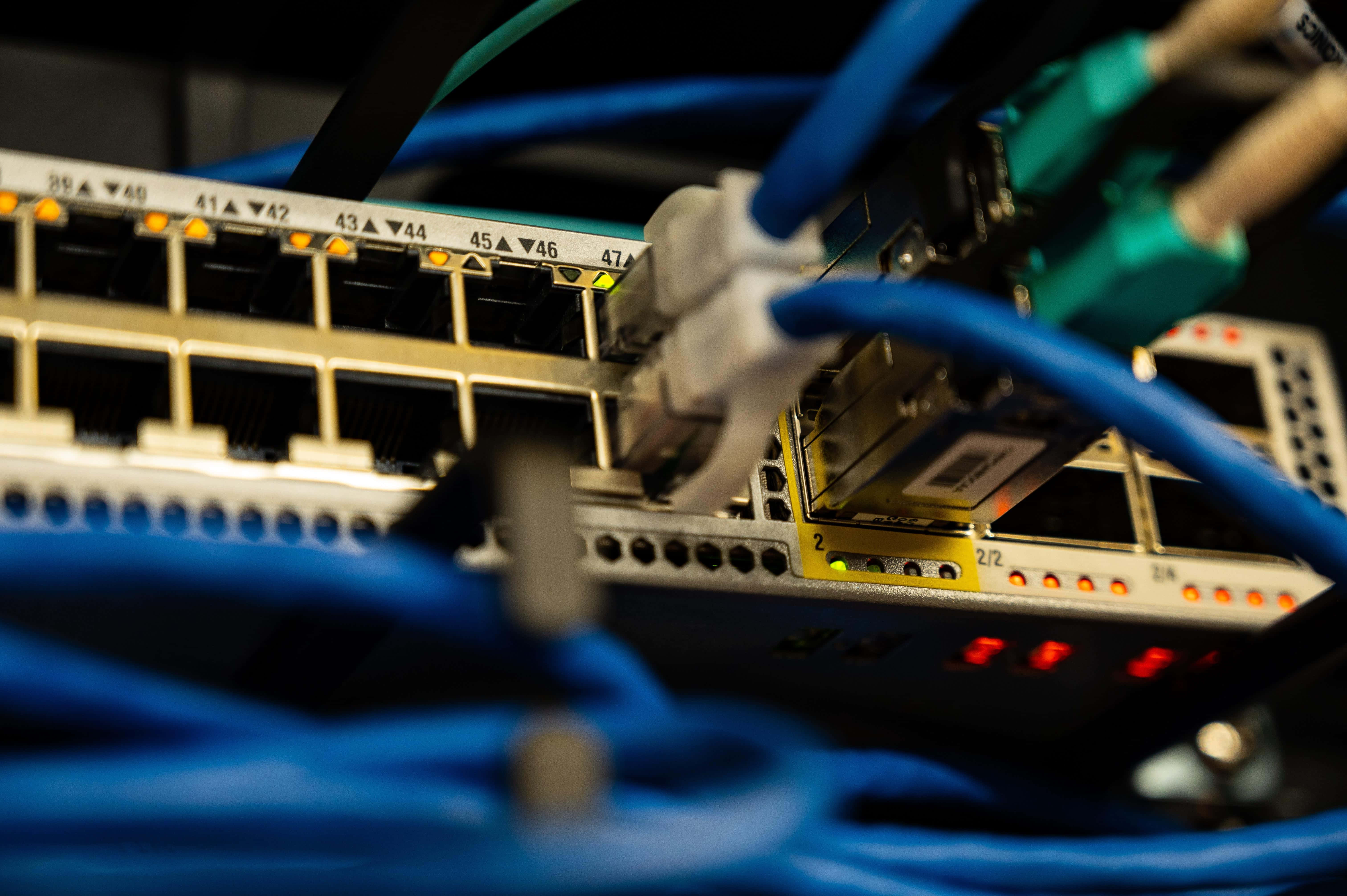 Ethernet 桌布 壁紙 — 網絡交換器特寫，插有藍色乙太網線，指示燈呈琥珀色和紅色發光。