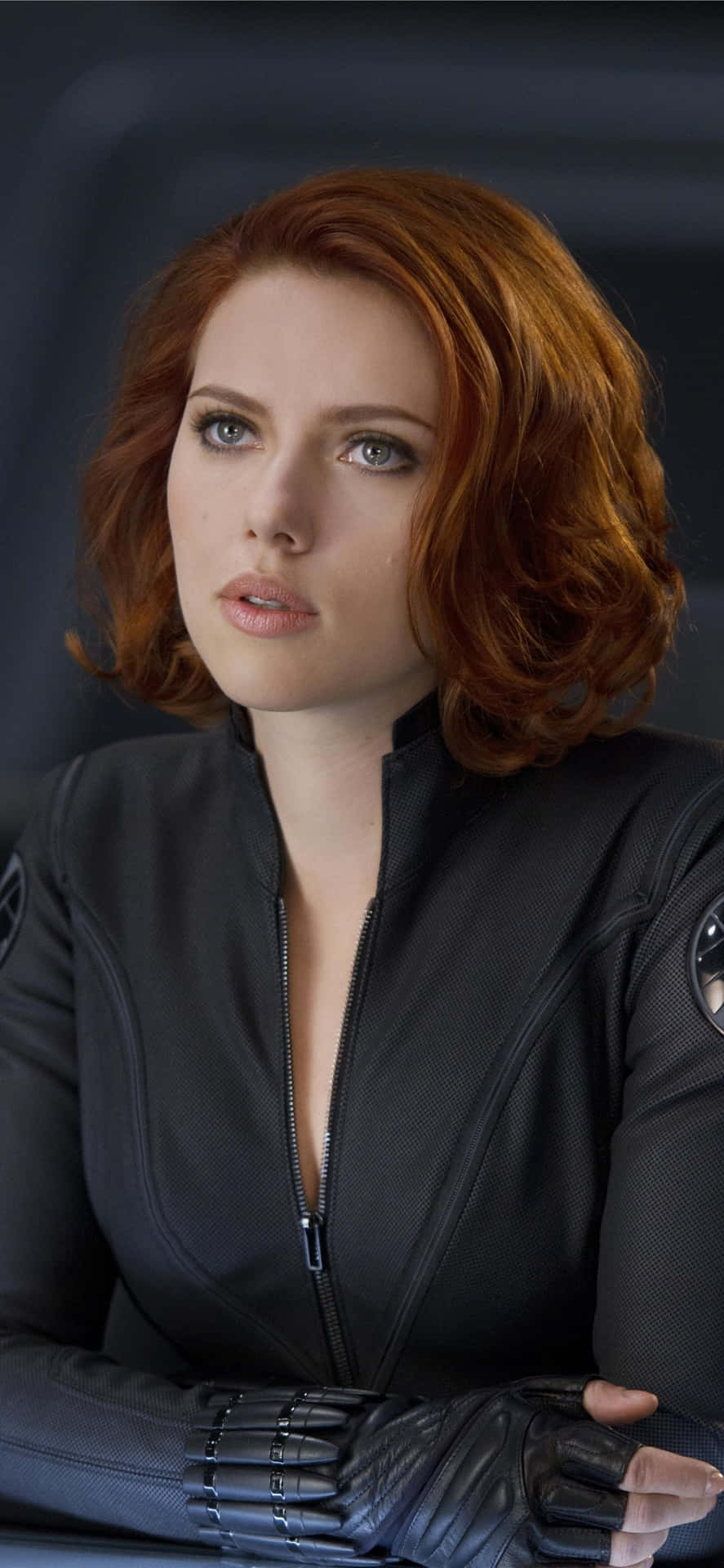 Natasha Romanoff 桌布 壁紙 — 緋紅女巫身穿黑色戰術服，紅髮，在深色背景下目光銳利。