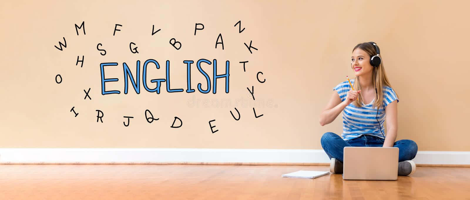 線上學習英語攝影藝術畫 壁紙 — 一位微笑的年輕女性盤腿坐在木地板上使用手提電腦，戴著耳機，身後牆上畫有「ENGLISH」和散落的字母。