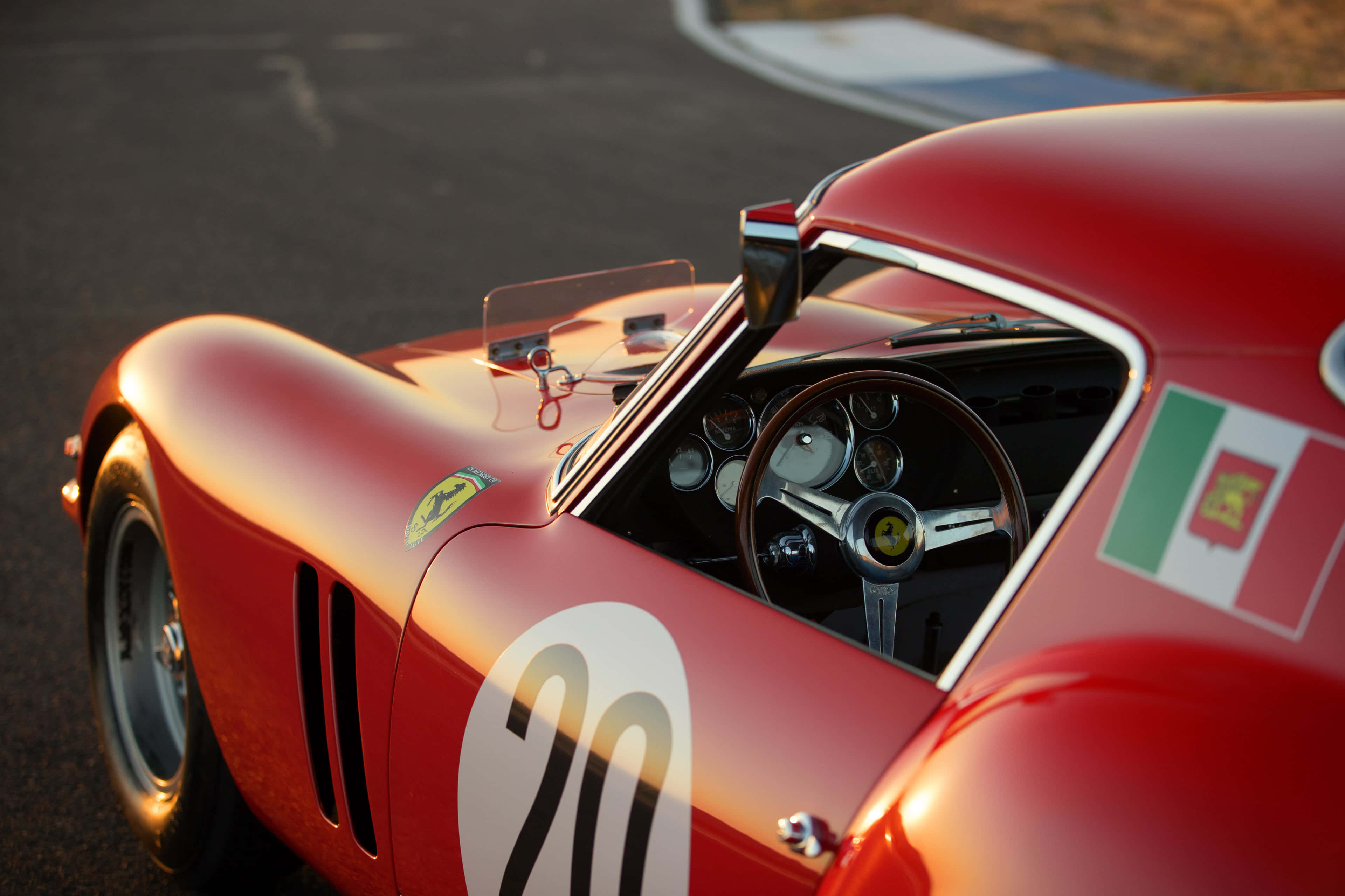 編號20的古董法拉利 壁紙 — 一輛復古紅色法拉利賽車，帶有20號和葡萄牙國旗，在黃金時段的賽道上閃閃發光。