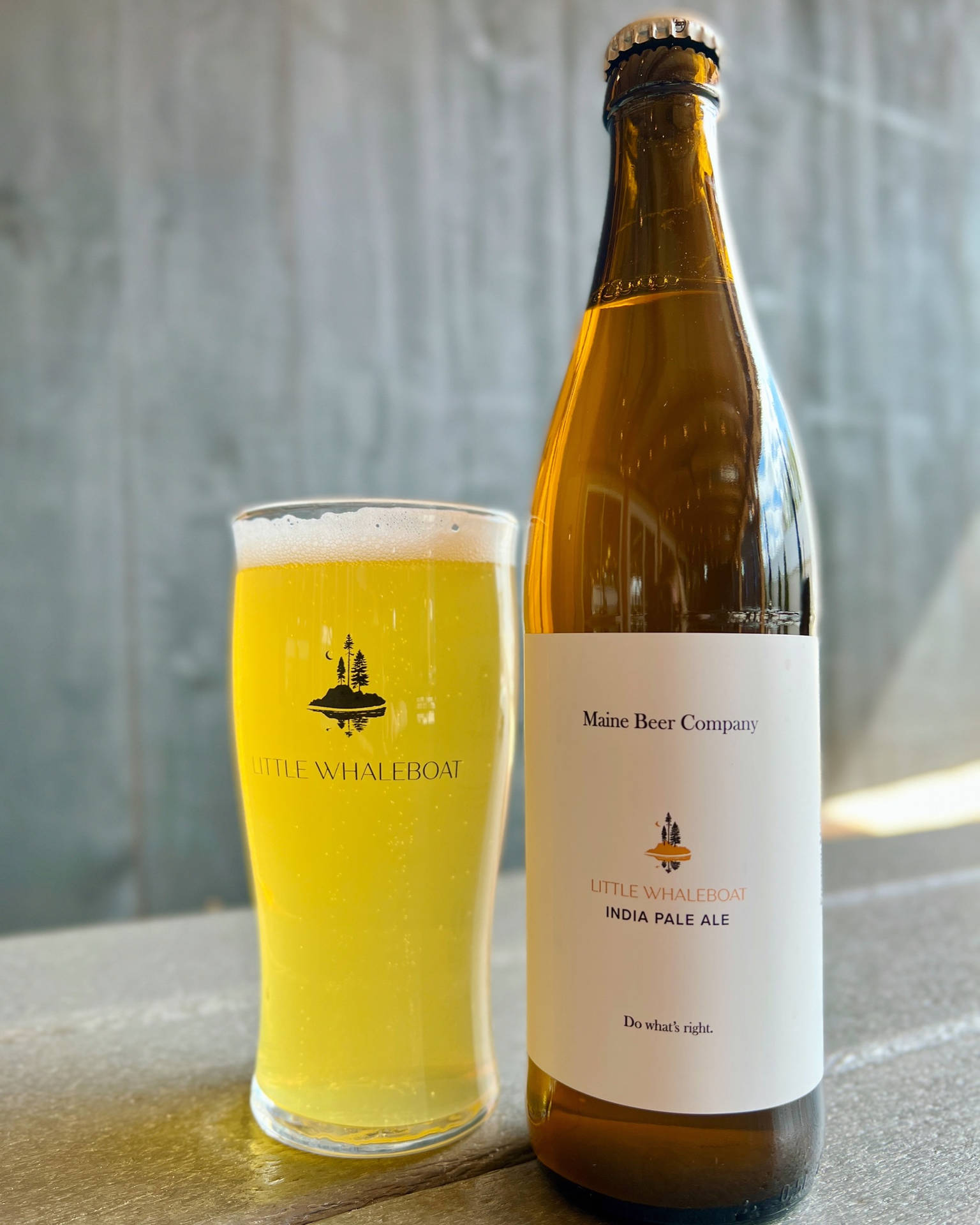 木桌上的一瓶及一杯Little Whaleboat India Pale Ale。