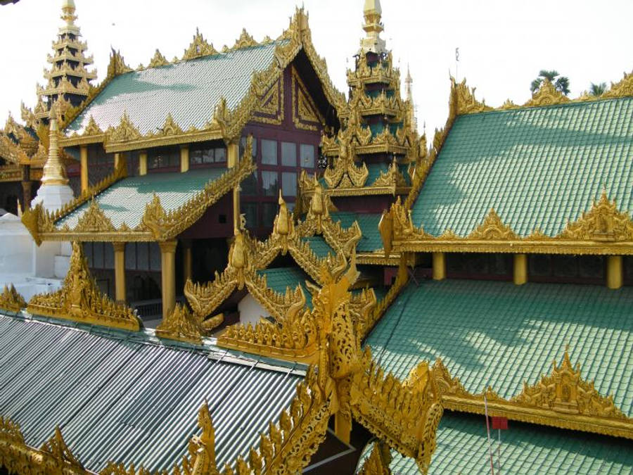 金色 桌布 壁紙 — 緬甸宏偉寺廟群的金色尖頂和青綠色屋頂在明亮的日光下閃閃發光。
