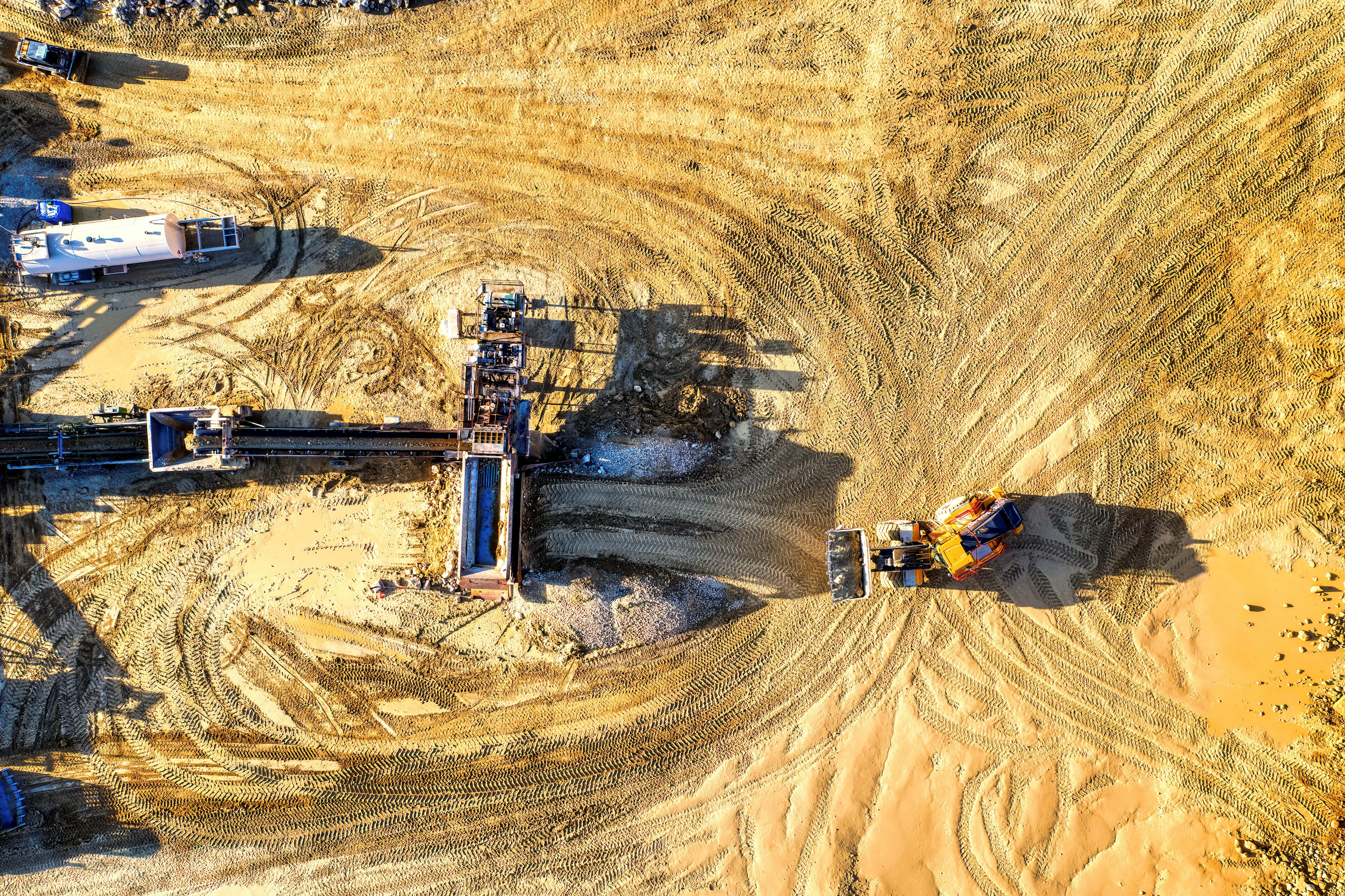 Mining 桌布 壁紙 — 繁忙建築工地的鳥瞰圖，重型機械在明亮的日光下移動泥土。