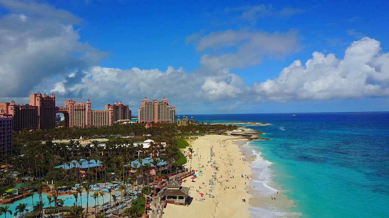 Bahamas Island 桌布 壁紙 — 繁忙的熱帶海濱度假村的鳥瞰圖，擁有碧綠的海水和粉紅色調的酒店，在明亮的藍天下。