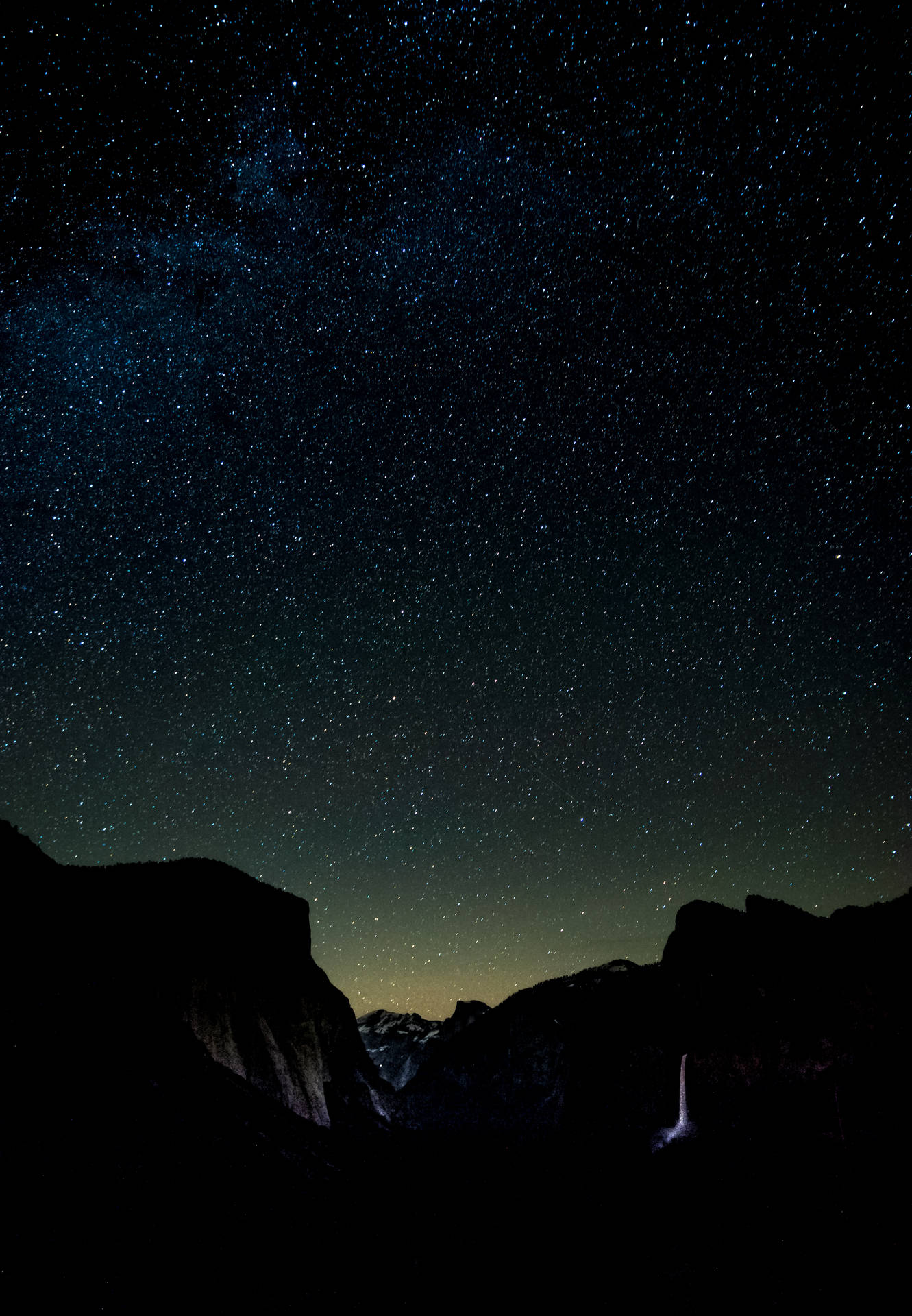黑暗山脈在星空夜空和銀河下框住發光瀑布。