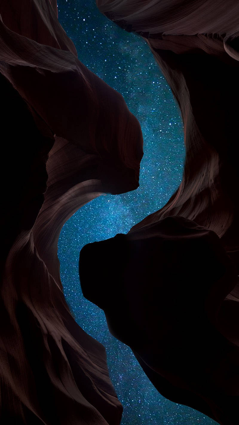 繁星夜空 iPhone 12 壁紙 — 狹窄的峽谷開口展現出由深紅色砂岩牆框住的鮮豔藍色星空。