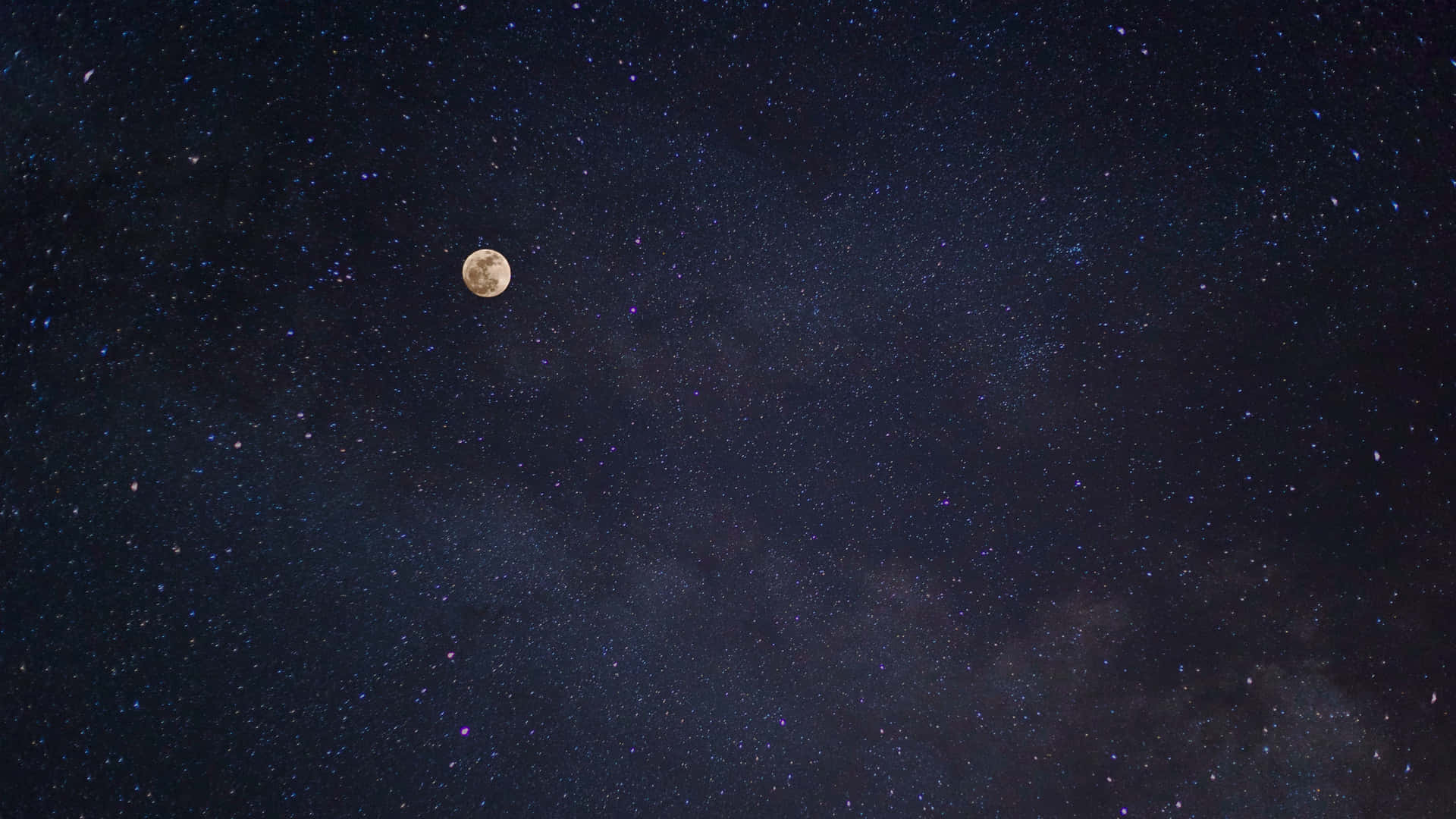 繁星夜空中的月亮圖 壁紙 — 一輪明亮的滿月在深邃的靛藍色夜空中，在密集的星星和宇宙塵埃中發光。