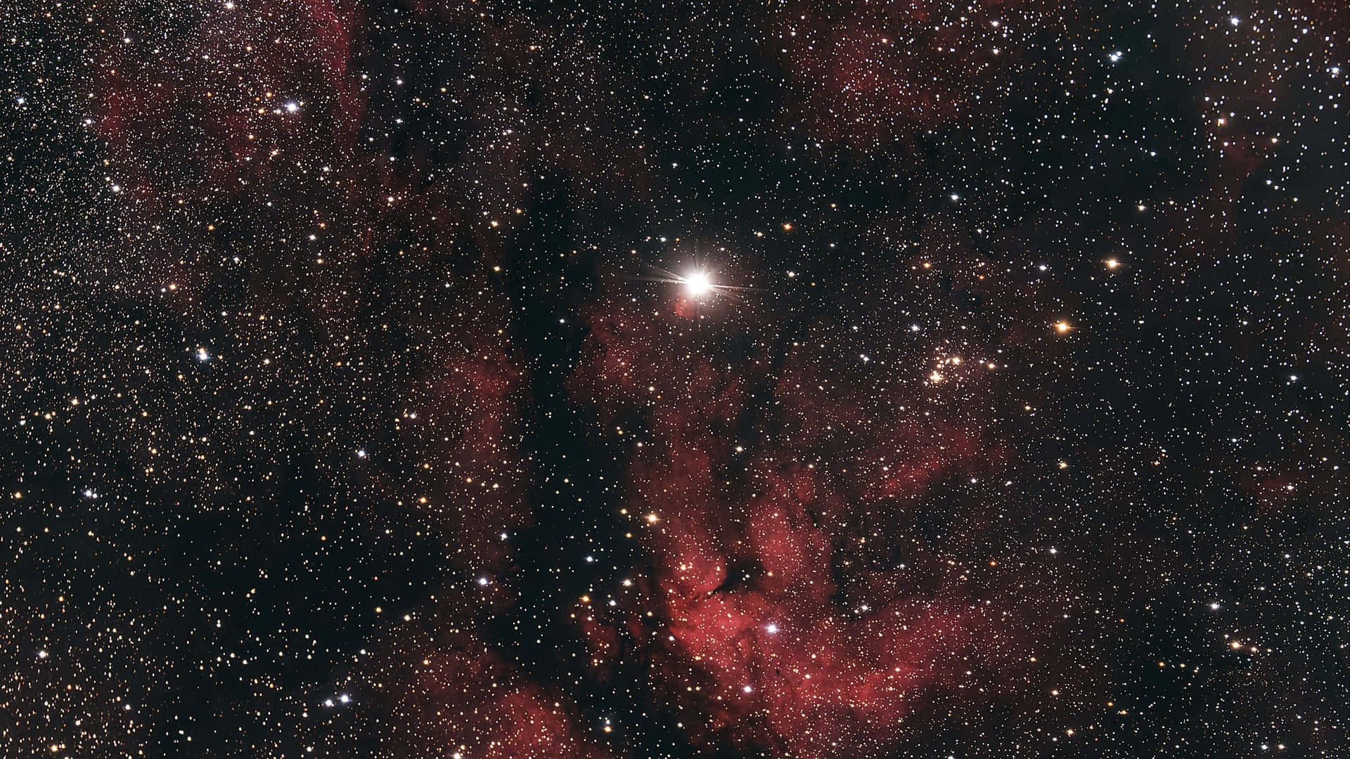 深空中鮮豔的紅色星雲和恆星，中央有一顆明亮的恆星。