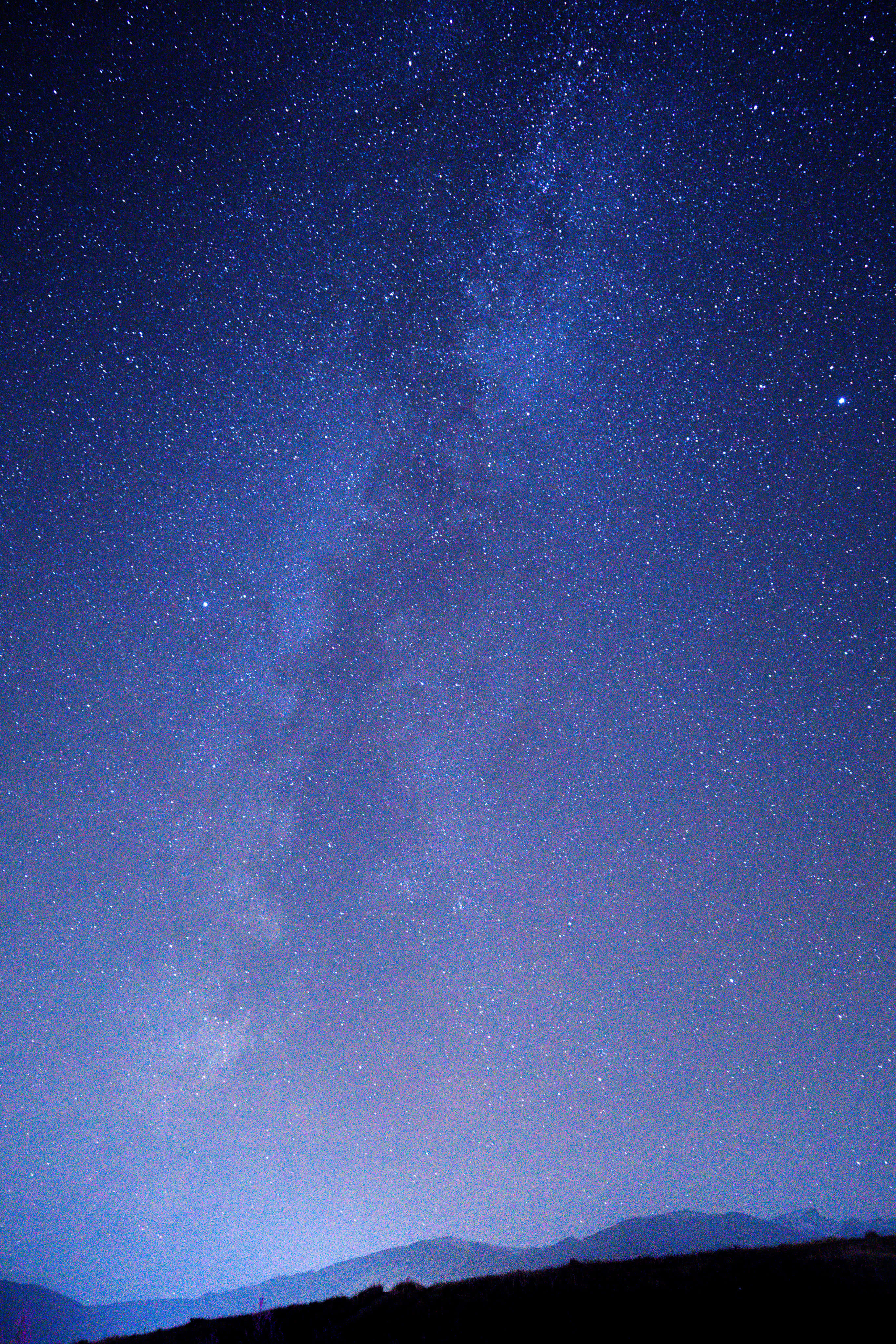 繁星夜空的壯麗之美 壁紙 — 令人嘆為觀止的銀河系景觀，在深藍色夜空下，橫跨在黑暗山脈剪影之上。