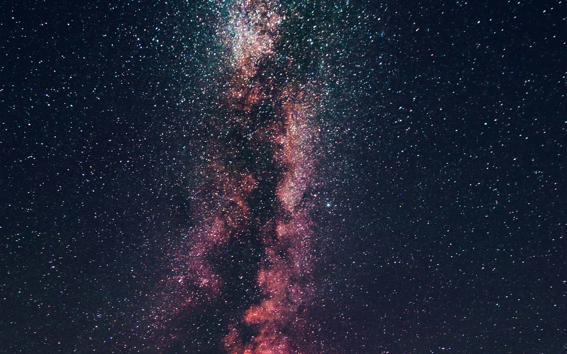 銀河系在繁星點點的夜空中散發粉紅和藍綠色星雲的光芒。