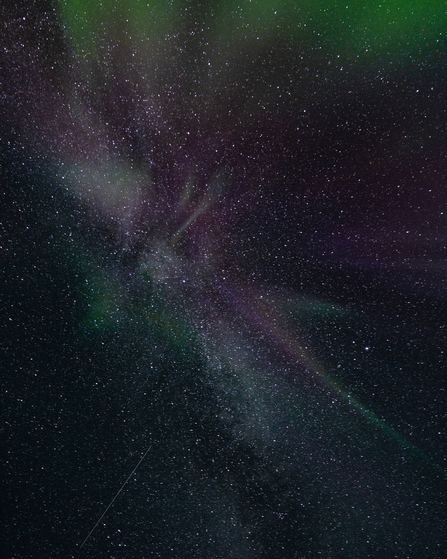 北極光在星空夜空中發出綠色和紫色的光芒。