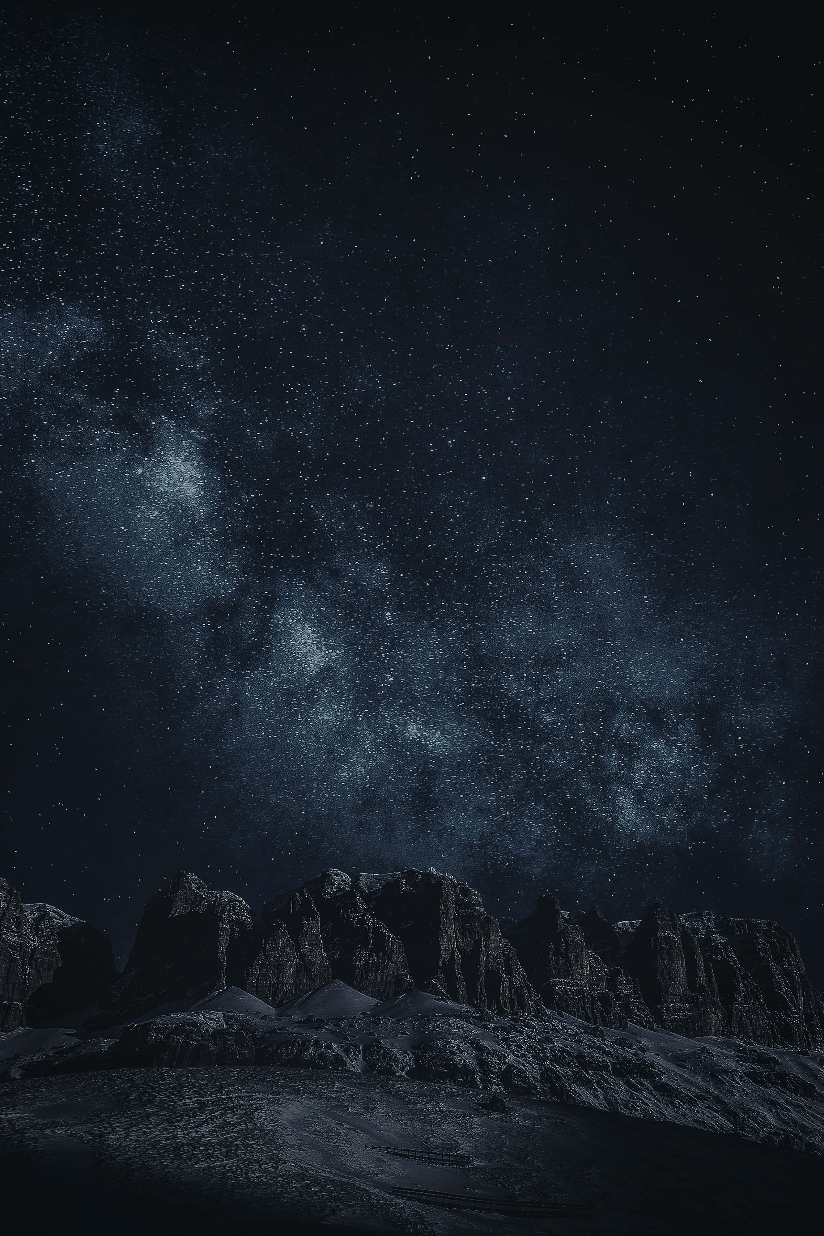 繁星與黑色岩層 iPhone 背景 壁紙 — 雄偉的雪山山脈在令人嘆為觀止的星空夜空下呈現剪影，銀河在上方閃耀。