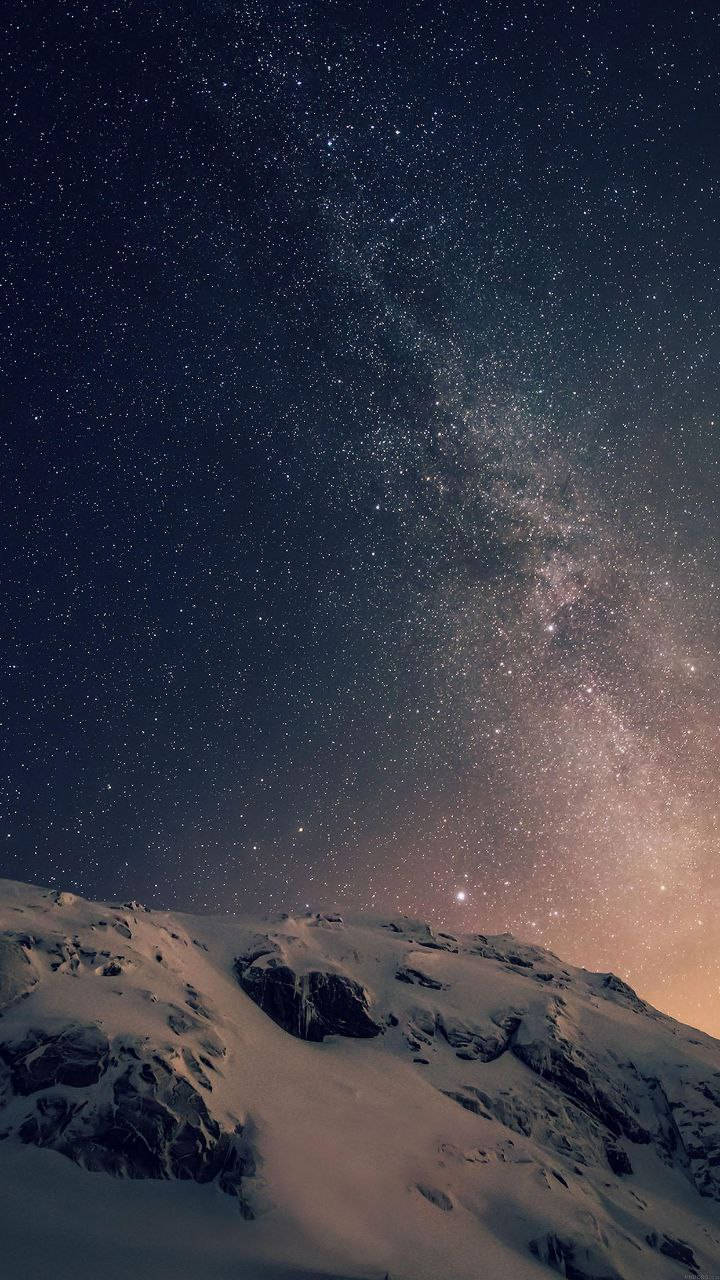 在可見銀河的星空夜空下，白雪覆蓋的山峰。