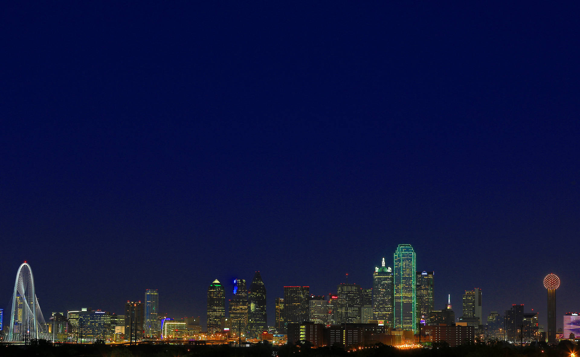 繁星點綴下的達拉斯天際線 壁紙 — 充滿活力的夜景城市景觀，摩天大樓燈火通明，摩天輪在深藍色天空下閃閃發光。