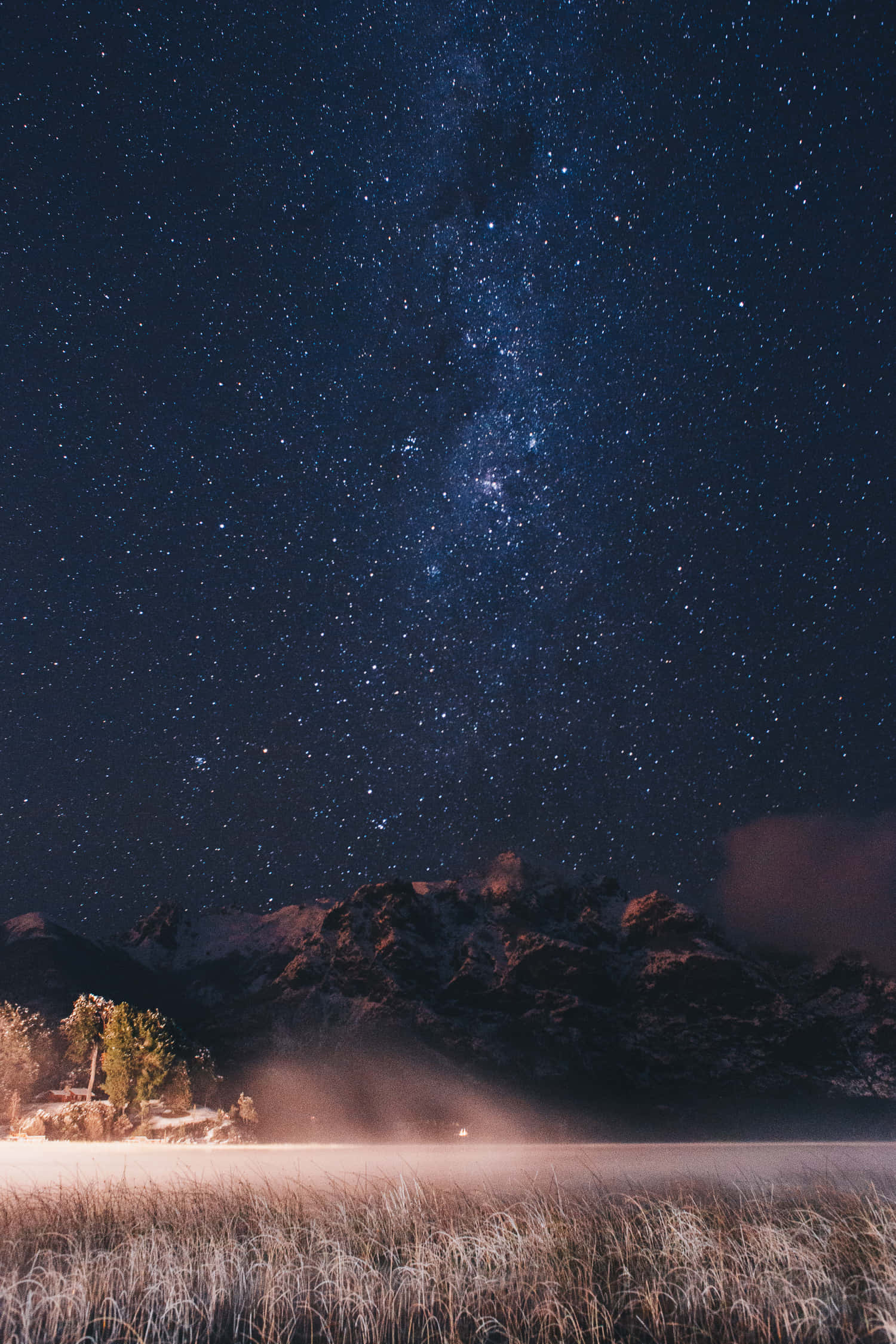 繁星點綴的夜空背景 壁紙 — 繁星點點的夜空，銀河拱跨雪覆山巒與霧氣瀰漫的冰凍湖泊。