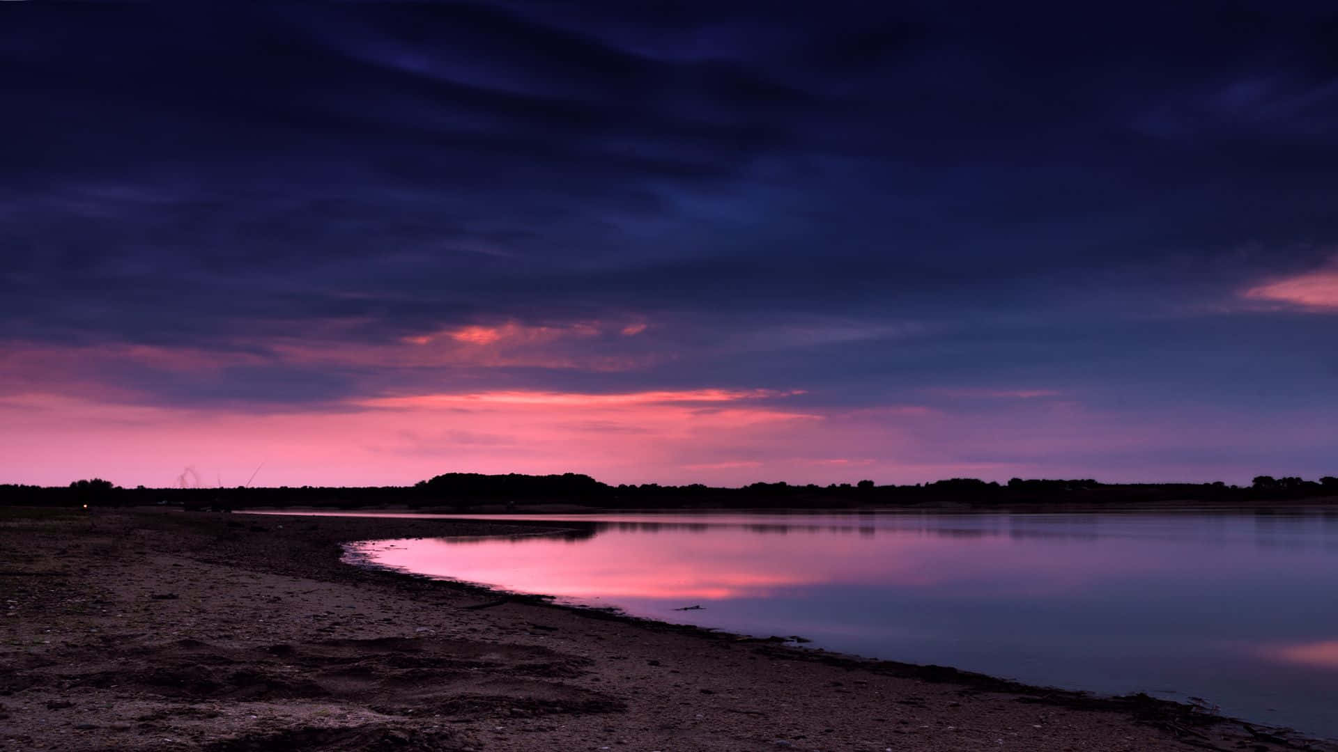 繁星點綴的寧靜海灘夜空 壁紙 — 黃昏時分，寧靜的湖面映照著漸暗天空中的鮮豔粉紅和紫色雲彩。