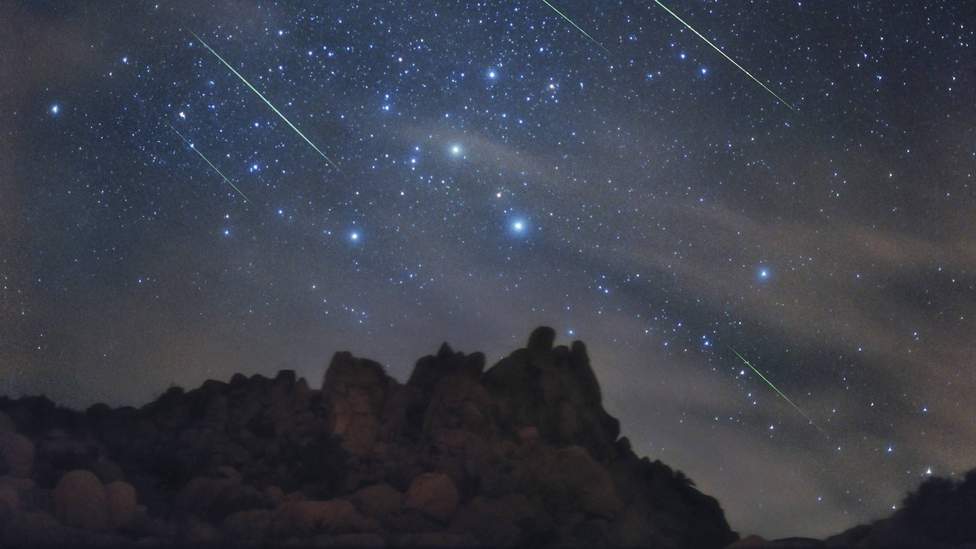 繁星點綴的美麗夜空 壁紙 — 崎嶇山脈剪影上劃過流星的星空夜空。