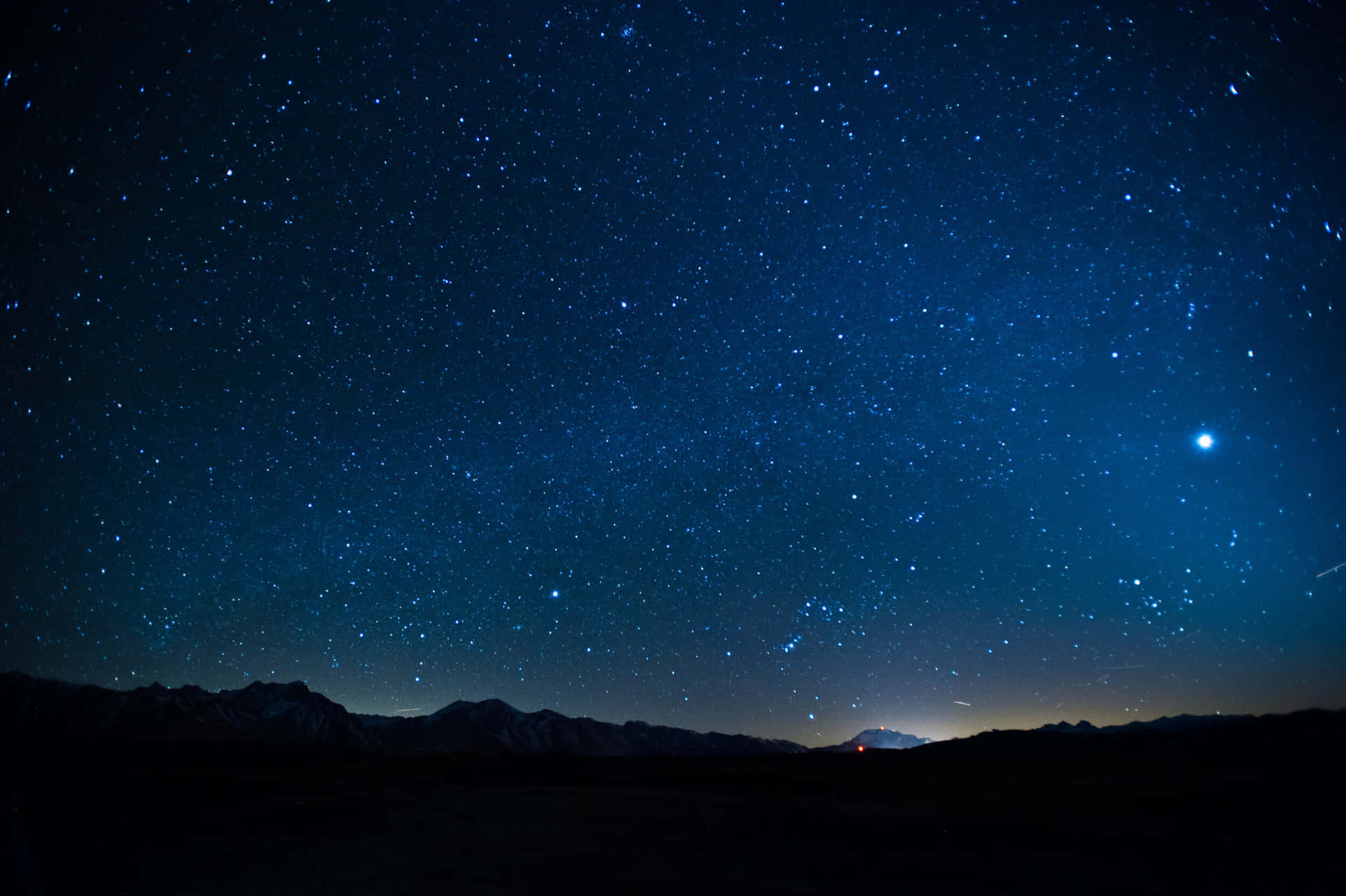 Aesthetic Night Sky 桌布 壁紙 — 繁星點點的夜空，一顆明亮的行星和隱約的銀河在黑暗的山巒剪影上方拱起。