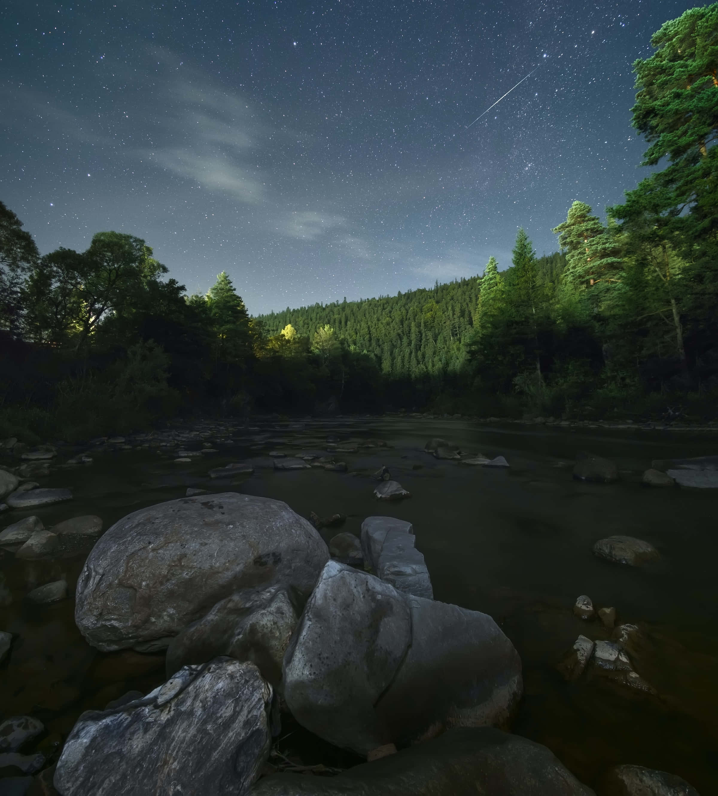 meteor 桌布 壁紙 — 繁星點點的夜空，一顆流星劃過平靜的河流，河流流經長滿苔蘚的岩石和茂密的森林。