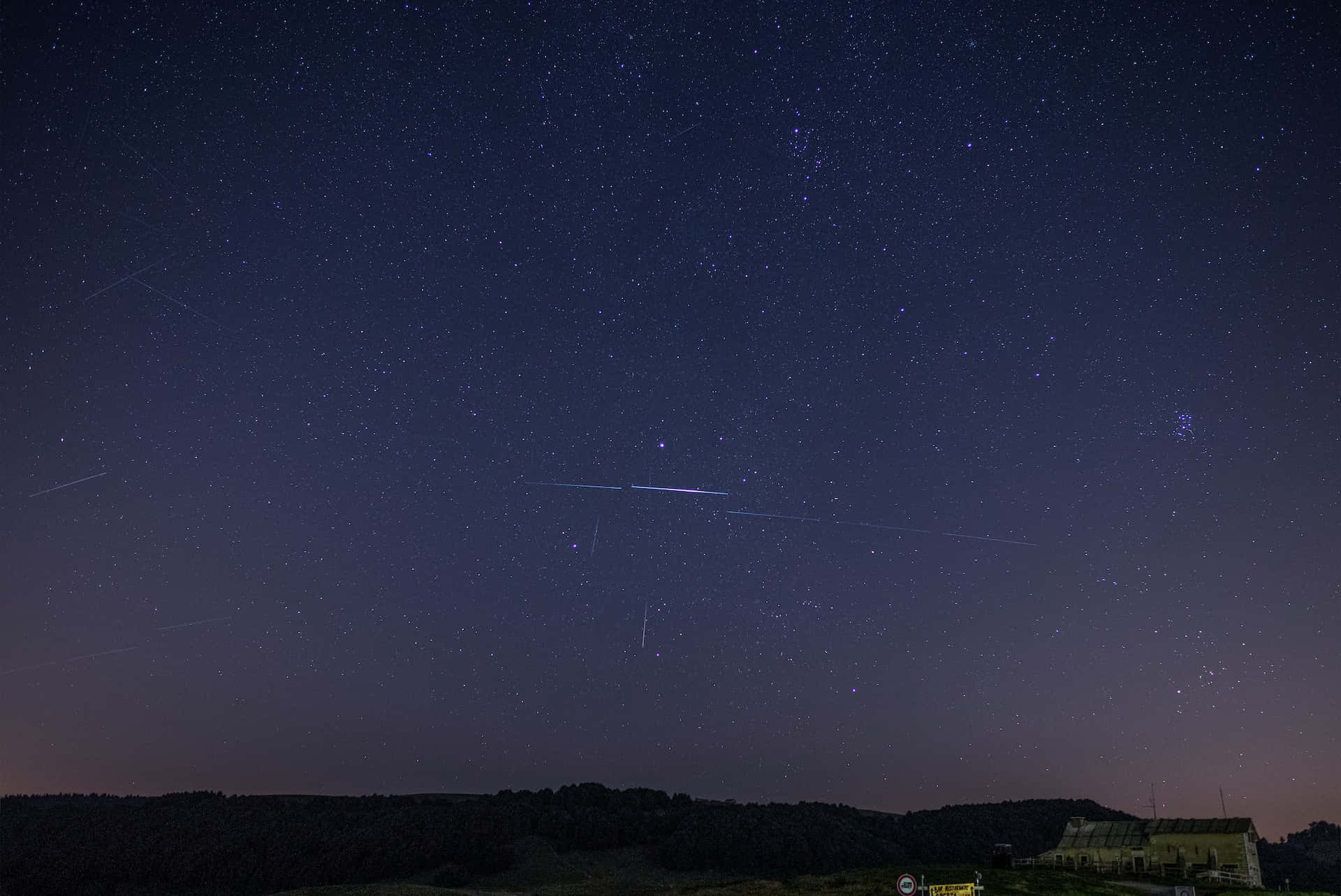 meteor 桌布 壁紙 — 繁星點點的夜空，流星軌跡劃過黑暗的山坡和一間孤獨的房子上方。