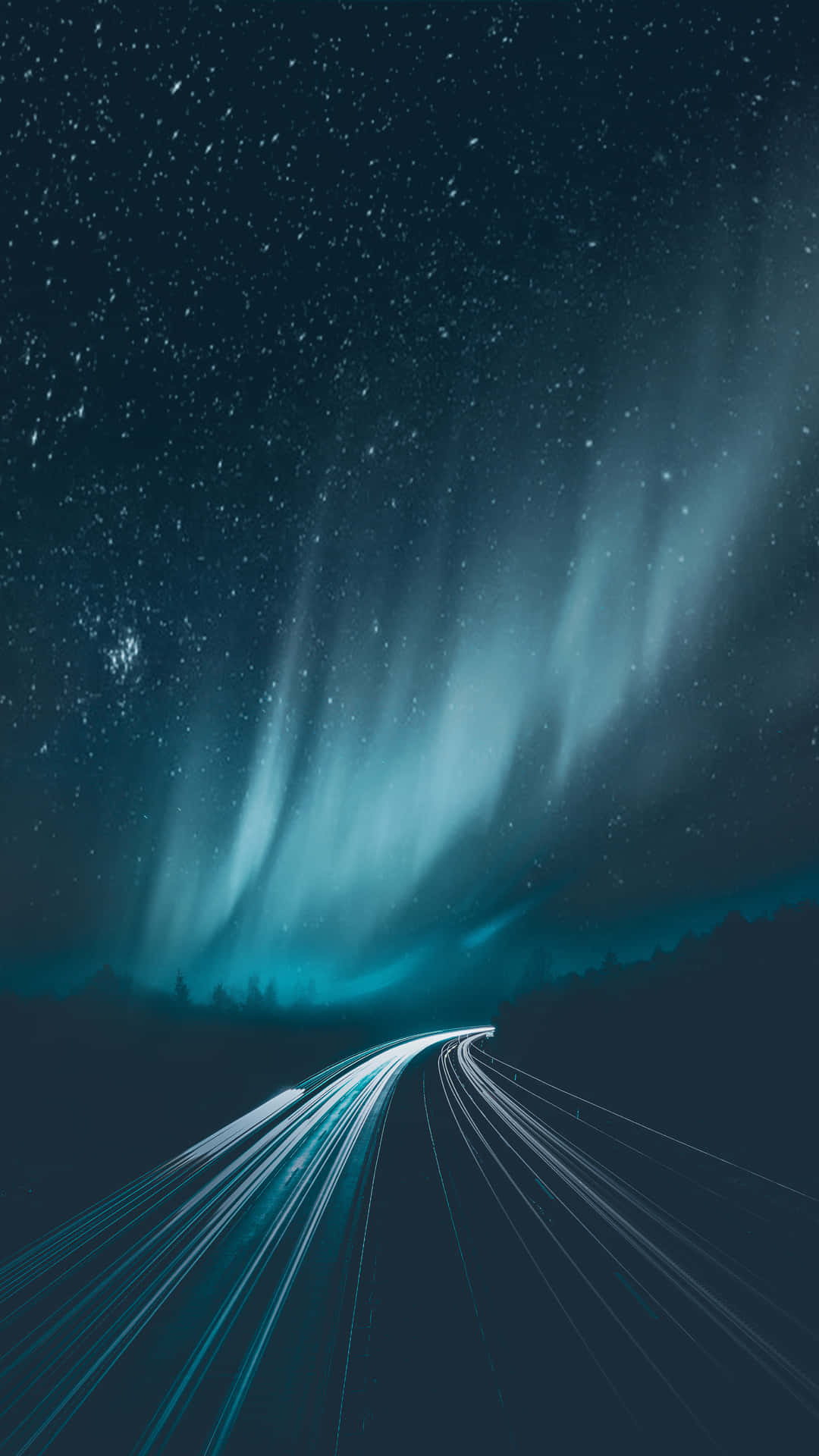 time lapse 桌布 壁紙 — 繁星點點的夜空，生動的極光拱形橫跨，蜿蜒的道路穿過黑暗樹林，留下一道發光的光跡。