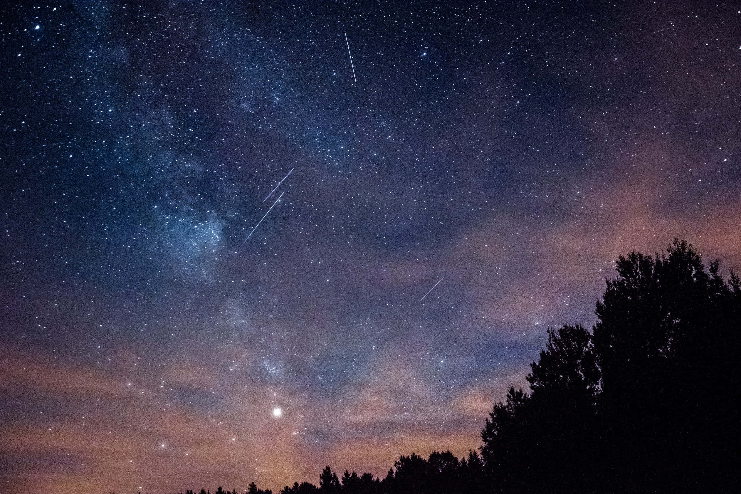 meteor 桌布 壁紙 — 繁星點點的夜空，發光的銀河和流星在黑暗的樹木剪影上方。