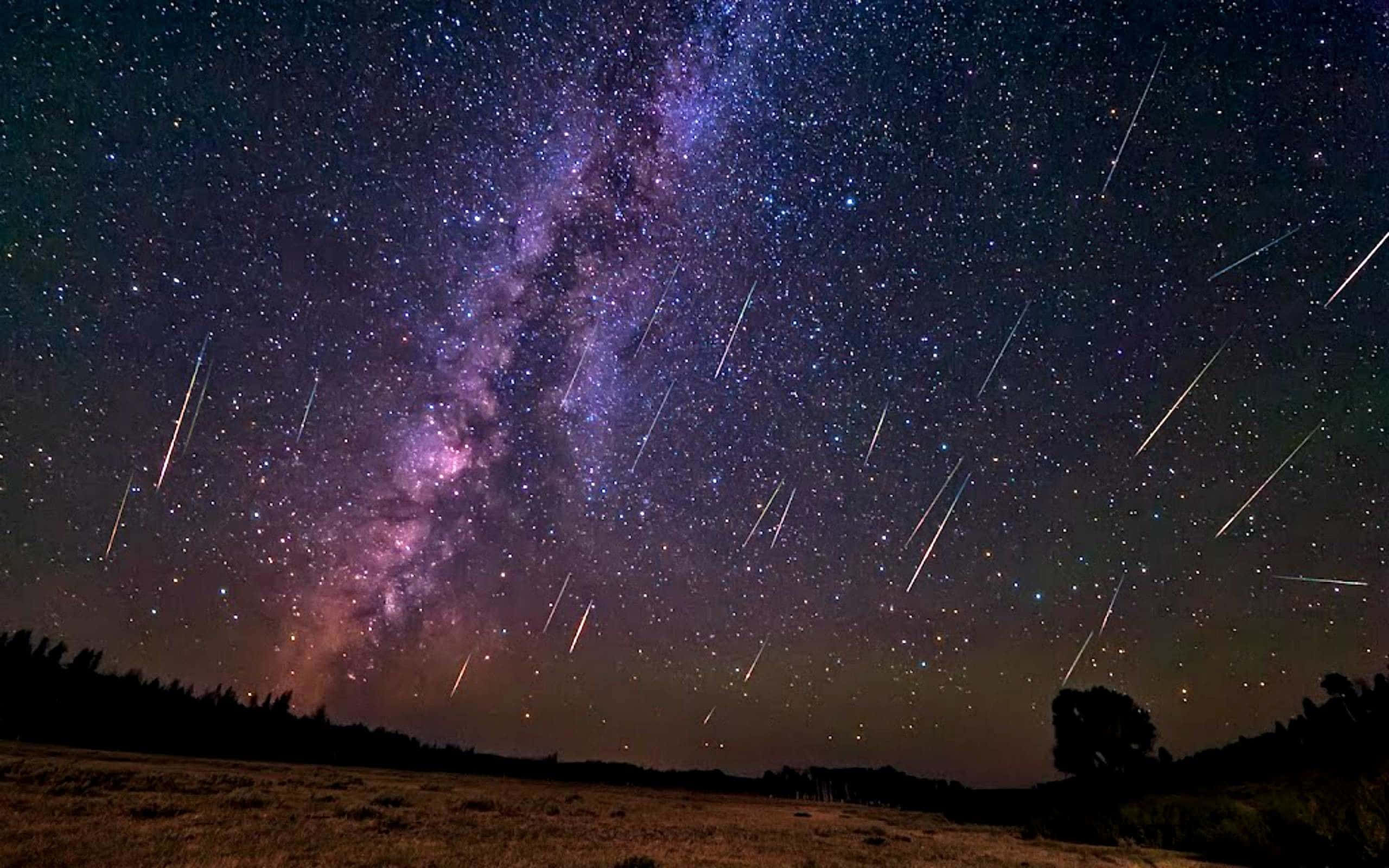 meteor 桌布 壁紙 — 繁星點點的夜空，銀河在黑暗的剪影田野上方閃耀著紫色和粉紅色，流星劃過天際。
