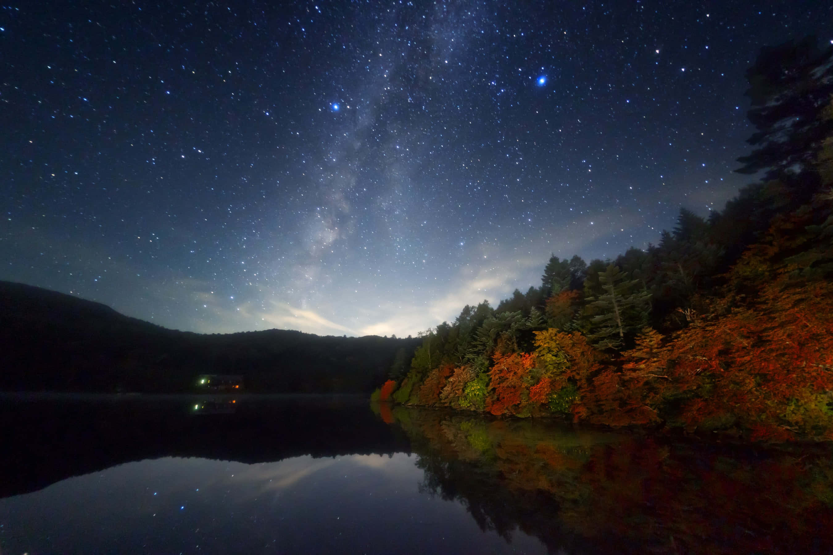 Fall River 桌布 壁紙 — 繁星點點的夜空，銀河拱起在平靜的湖面上，倒映著秋天的樹木和遠山。
