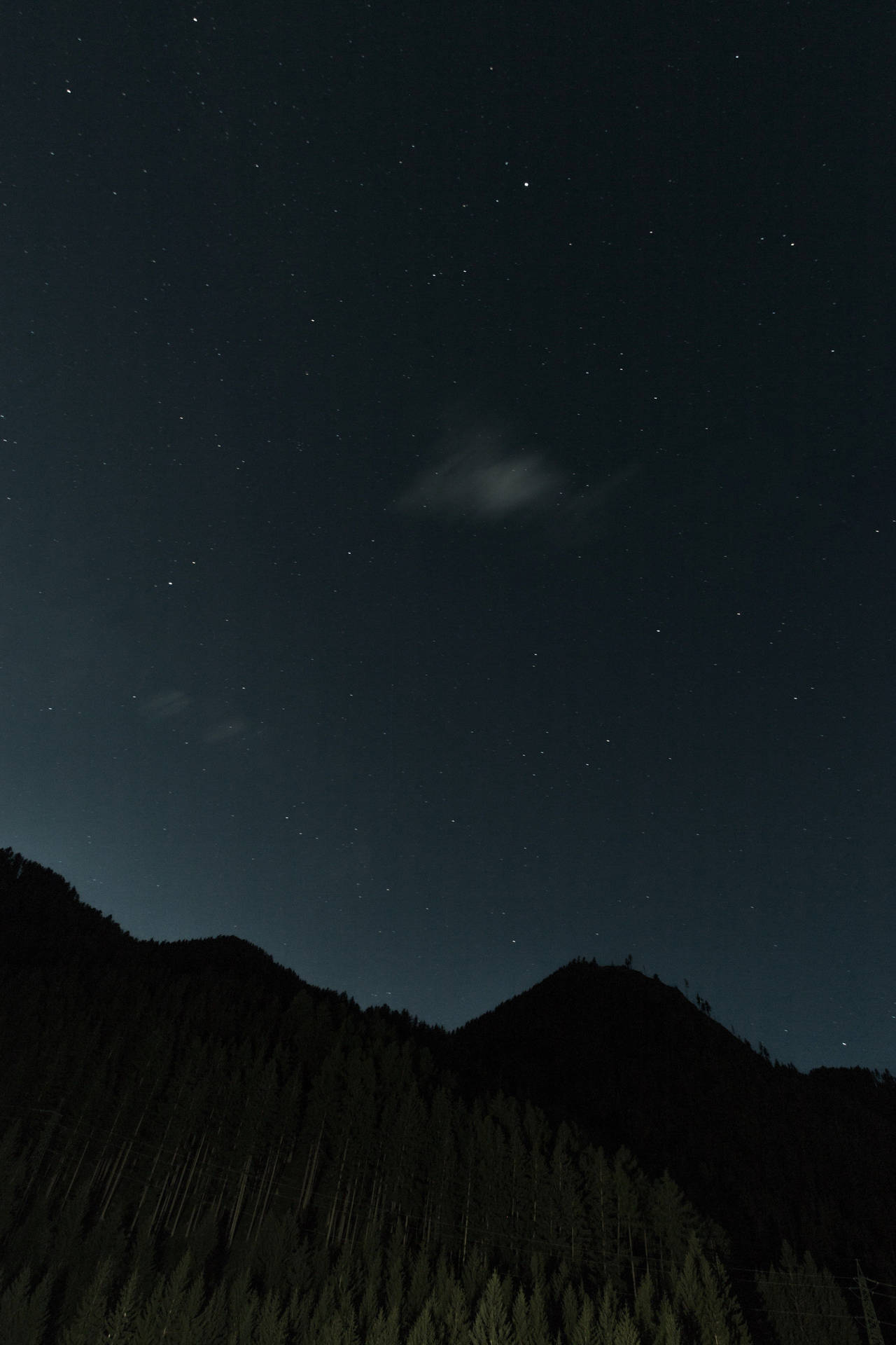 繁星點點、薄雲輕飄的夜空下，黑暗森林覆蓋的山巒。