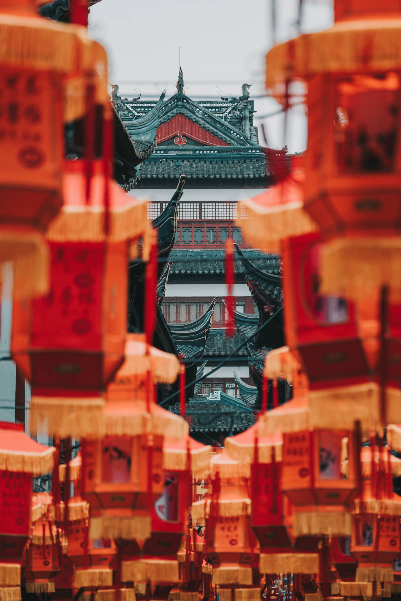 紅色燈籠掛在傳統中國寶塔前，寶塔有瓦片屋頂。