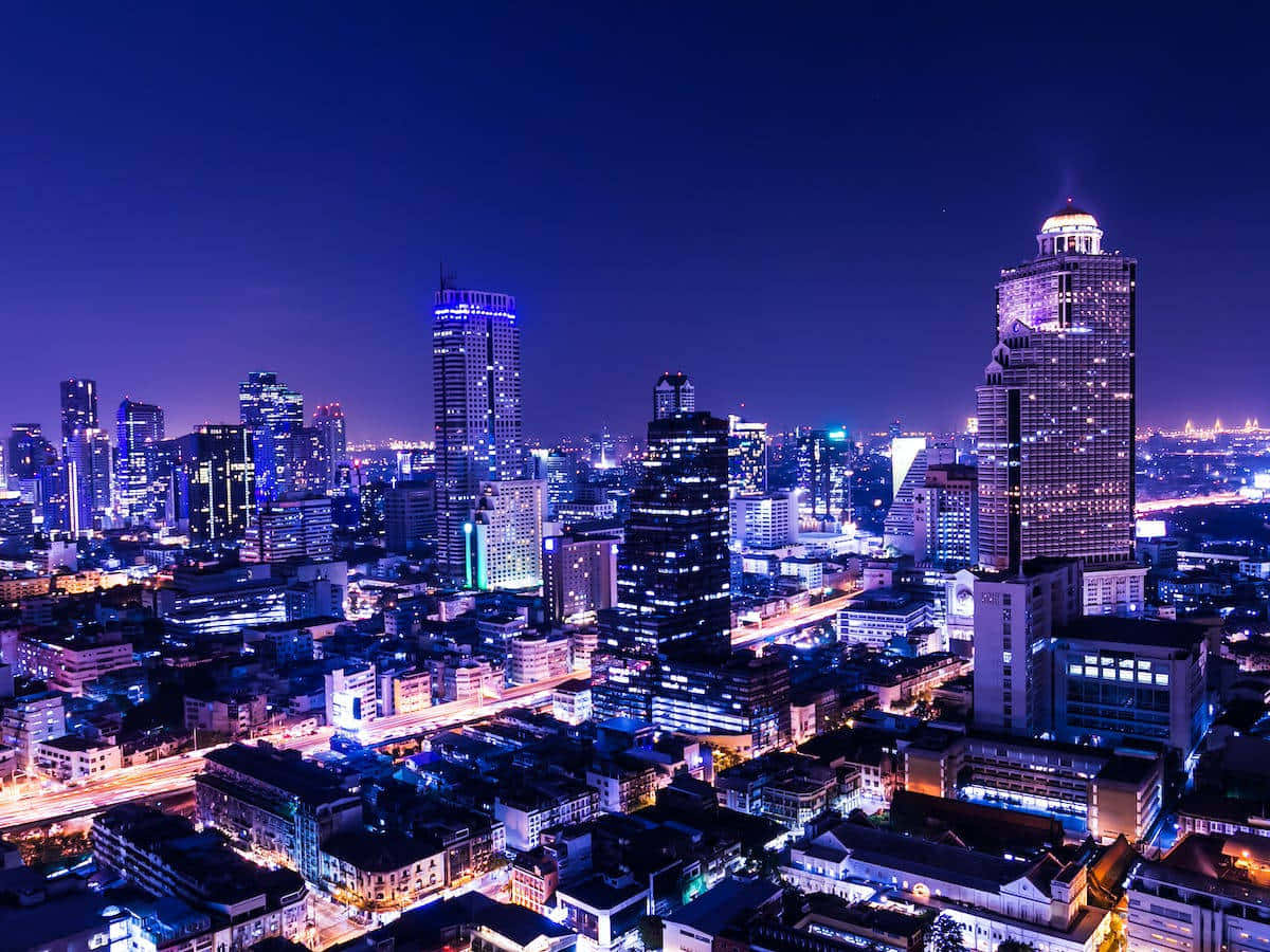 繁華城市夜景 壁紙 — 從高空俯瞰充滿活力的城市夜景，高聳的摩天大樓在深藍色天空下閃耀。