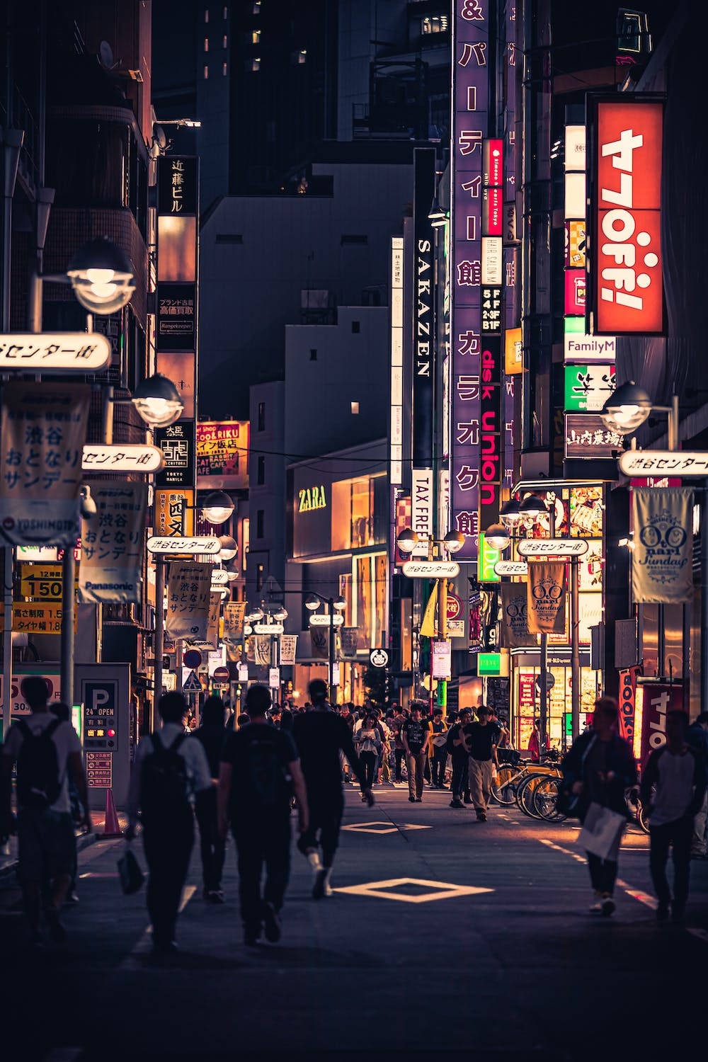 夜晚東京嘅霓虹燈街道，有行人同發光嘅招牌。