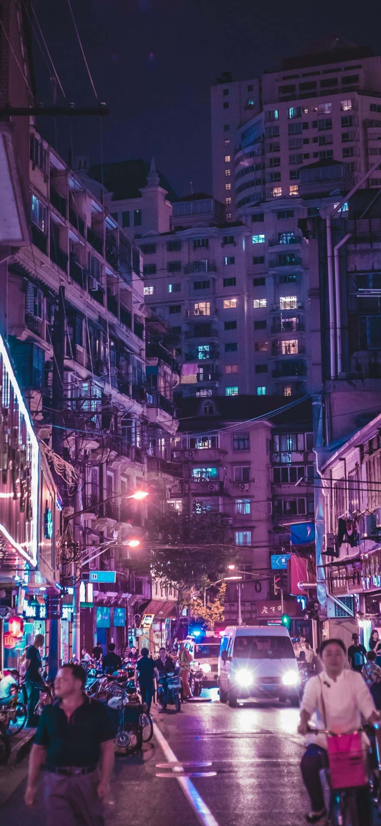iPhone XS Max 桌布 壁紙 — 繁華的霓虹燈城市小巷夜景，有行人、騎單車者和發光的商店櫥窗，天空漆黑一片。